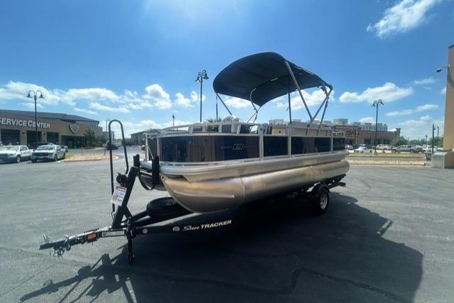2026 Sun Tracker Bass Buggy 18 DLX pontoon boat on trailer under clear sky.