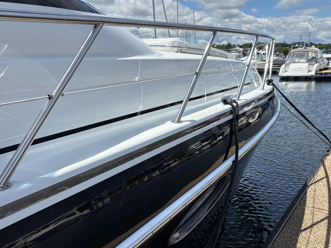 A sleek white yacht with shiny metal railings docked on a sunny day in the harbor.
