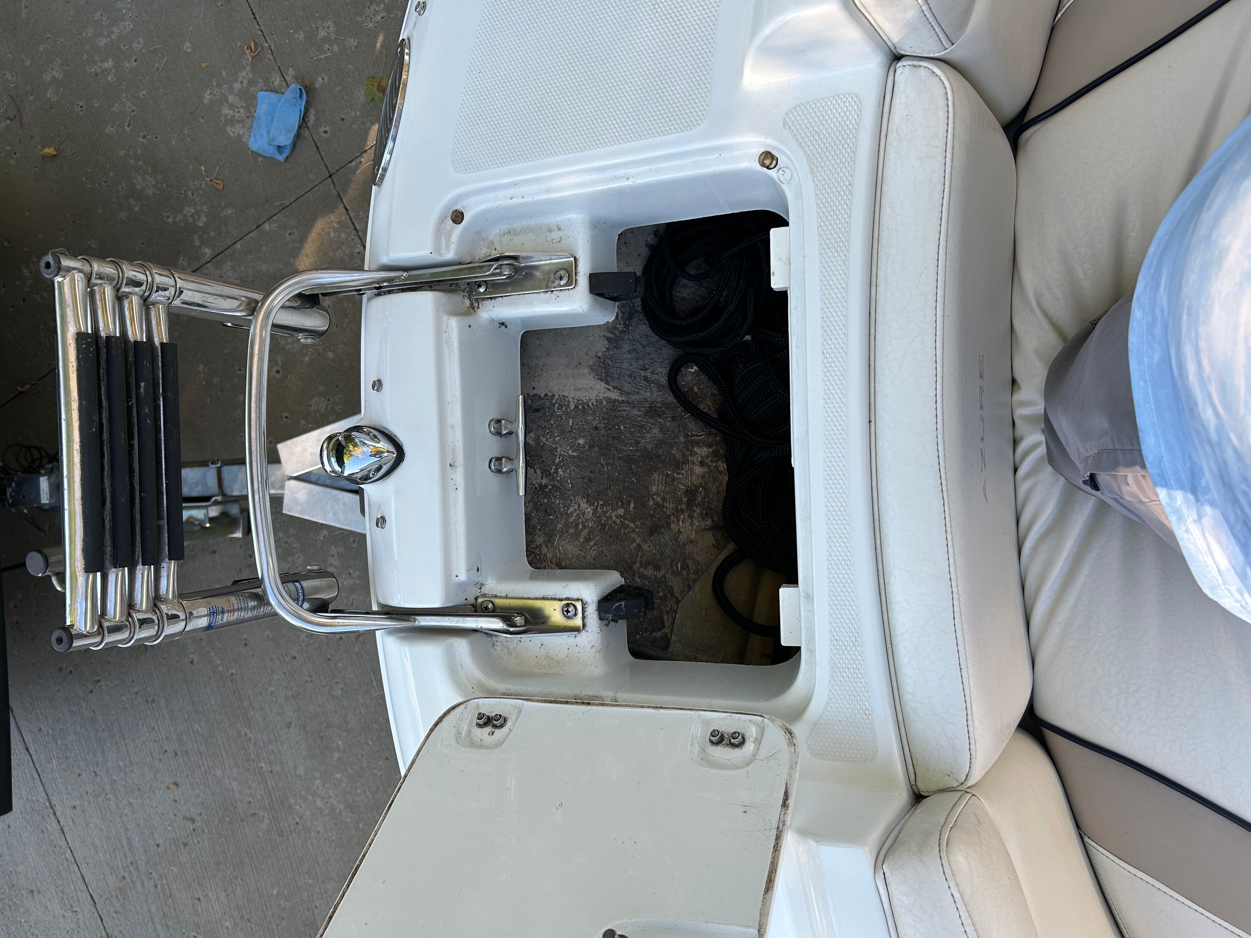 An open storage compartment on a boat with a ladder and white upholstery.