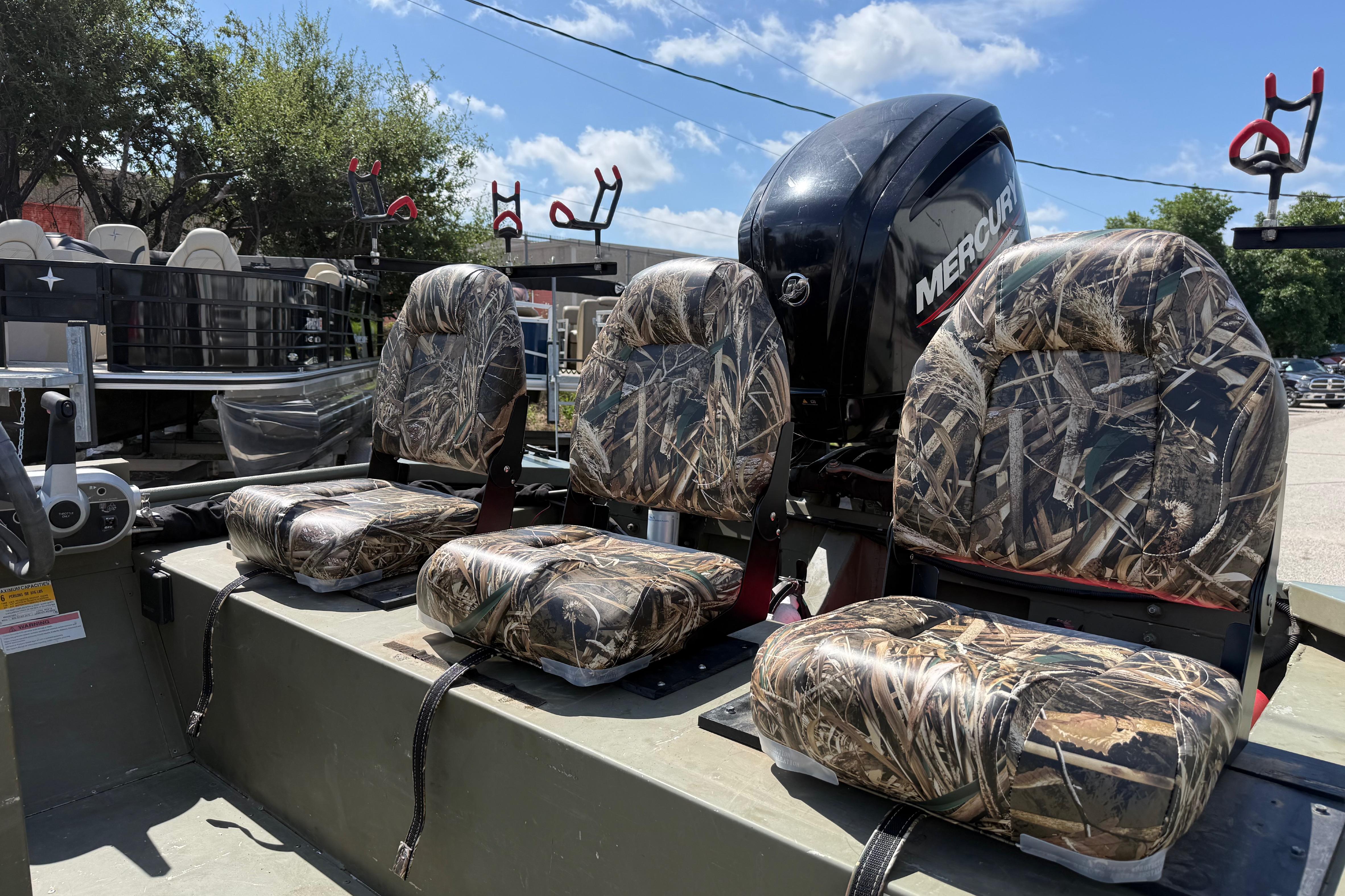Three camouflage seats on a boat with a Mercury engine in the background.