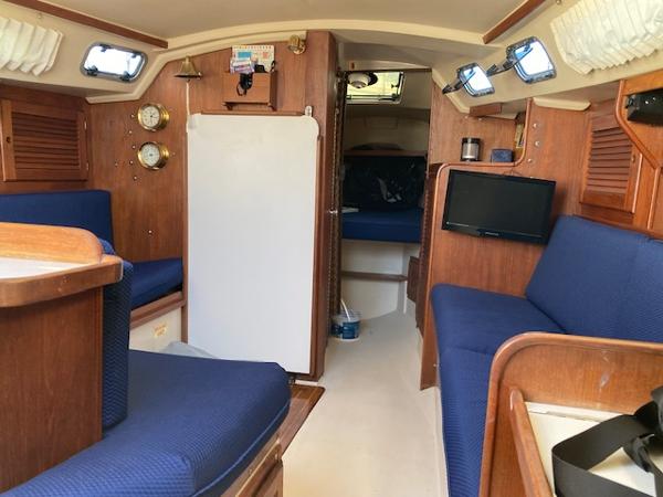Interior of a 1989 Catalina 30 sailboat with blue seating and wooden accents.