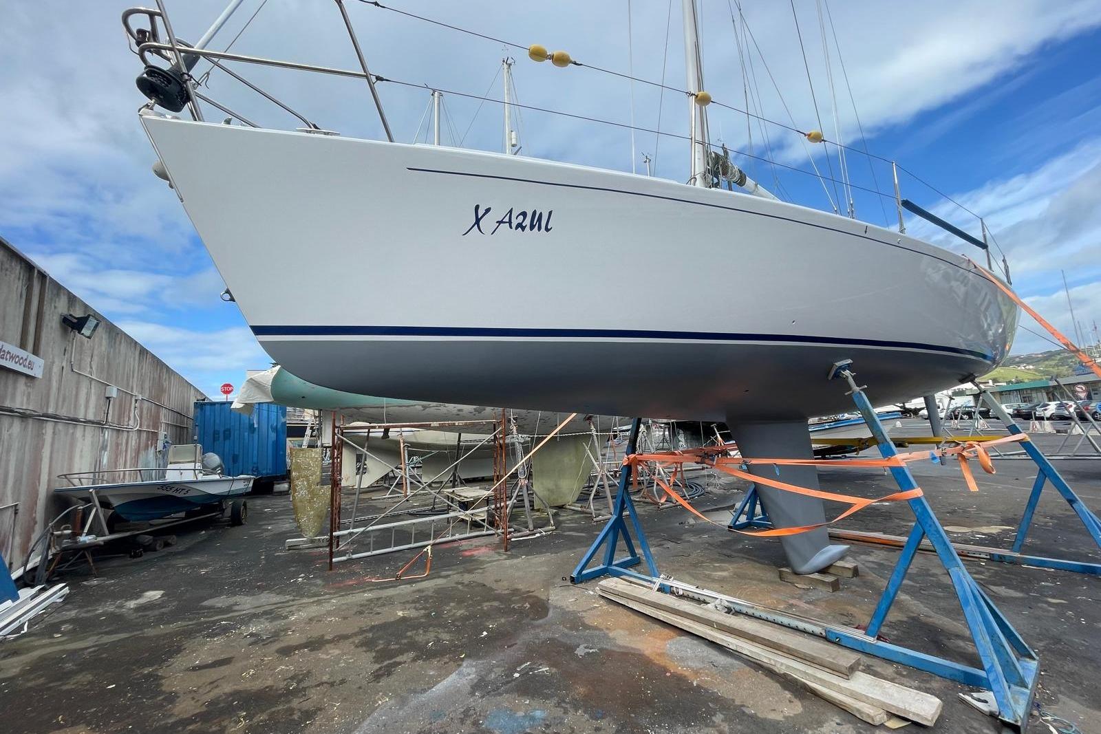 2001 J Boats J/105 sailboat on stands in a boatyard, clear sky background.