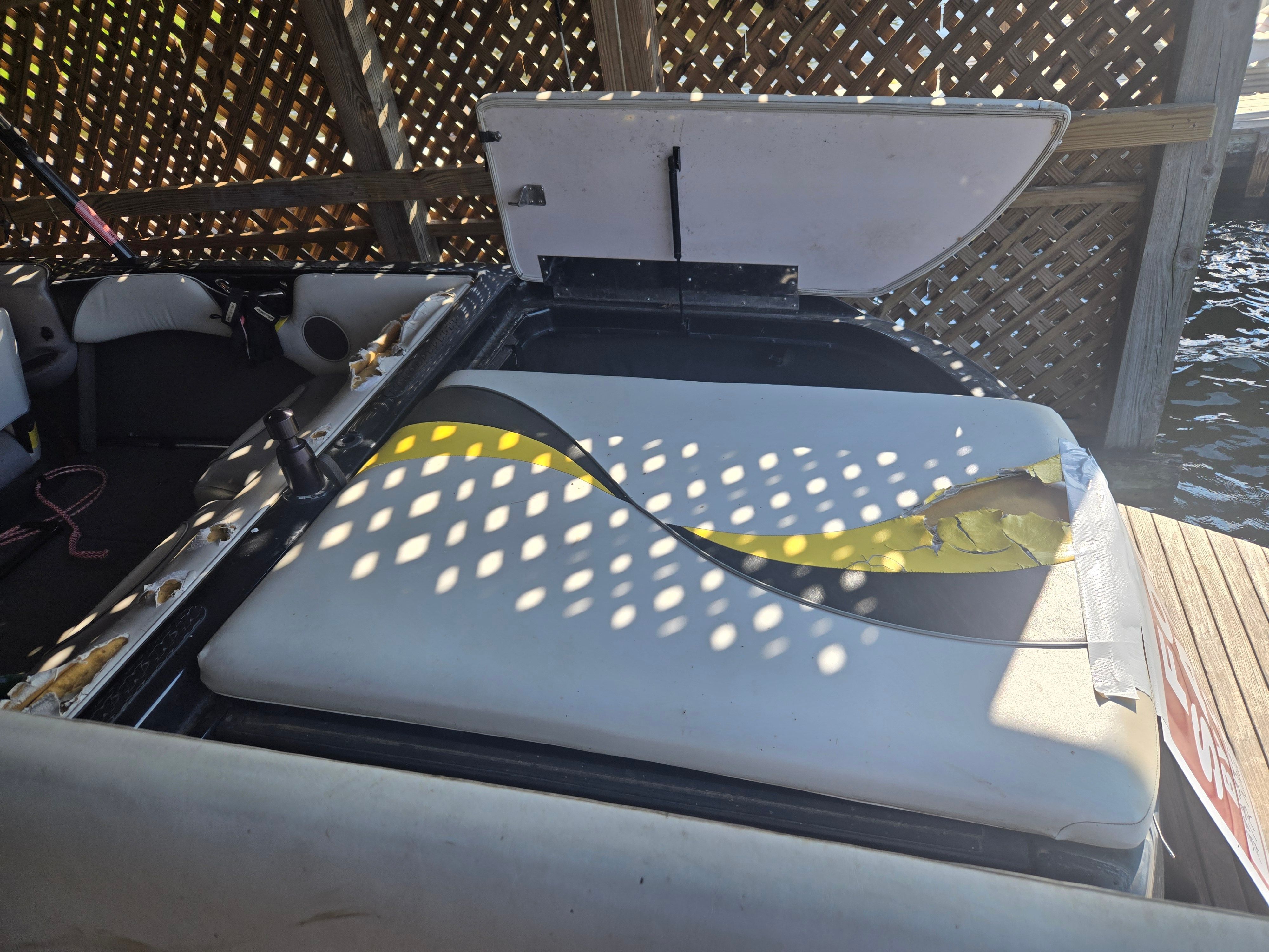 A 2003 Correct Craft Air Nautique with damaged seat upholstery in a covered area.