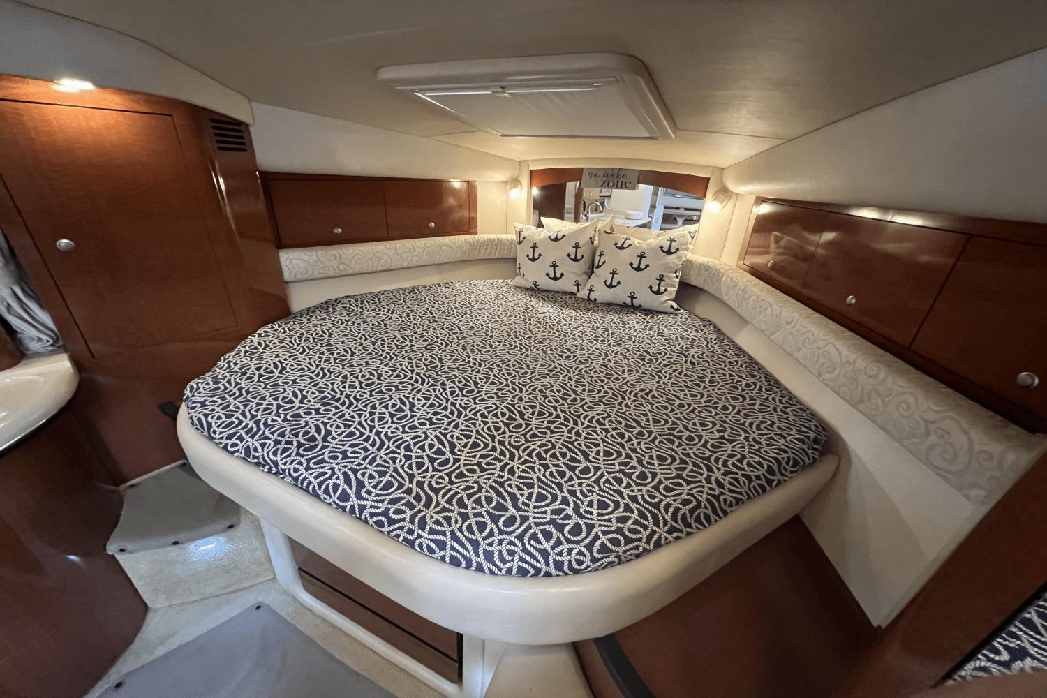 Luxurious cabin interior of 2005 Sea Ray 340 Sundancer with patterned bedding and anchor-themed pillows.