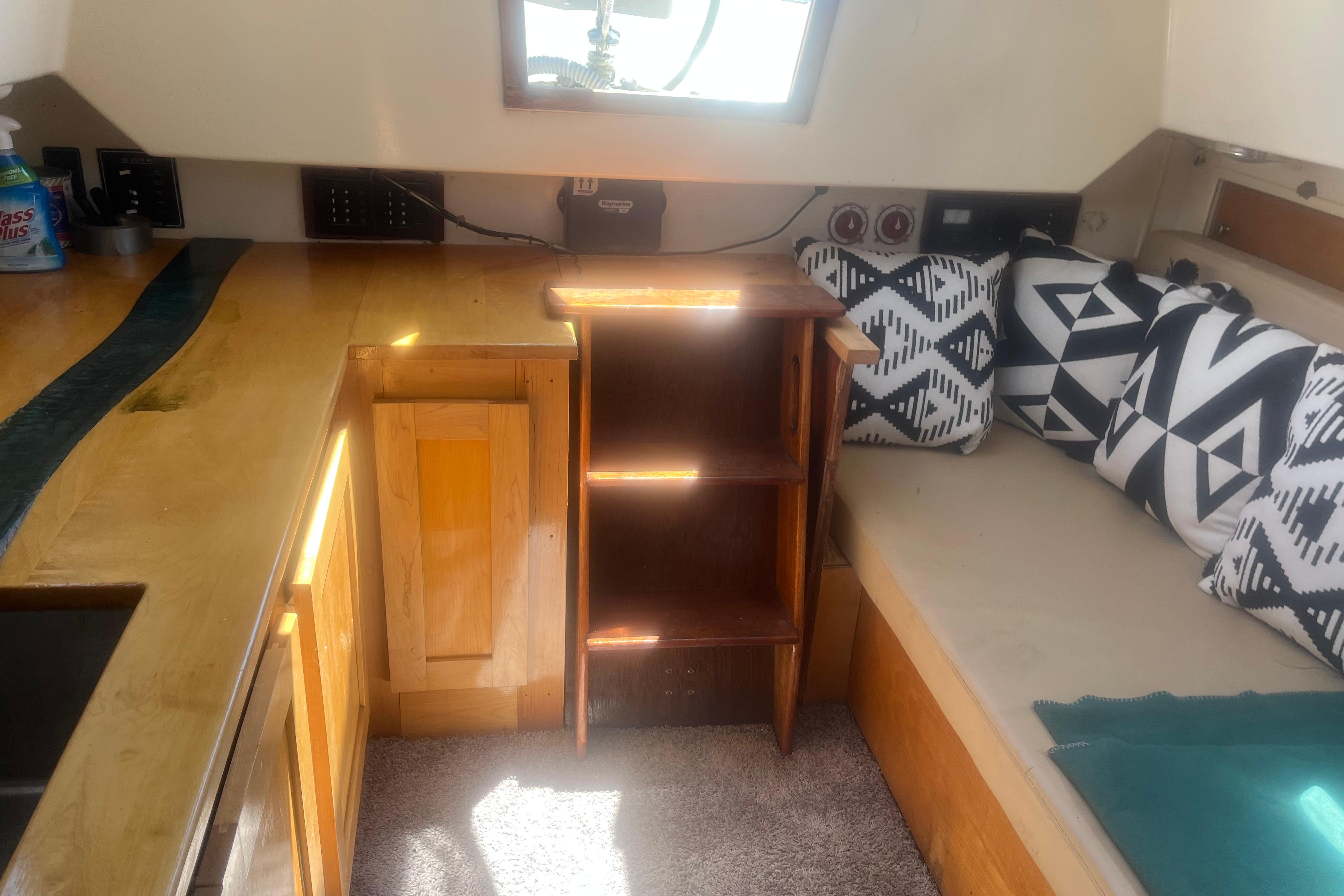 Interior of a 1972 C&C 30 sailboat with wooden cabinetry and patterned cushions.