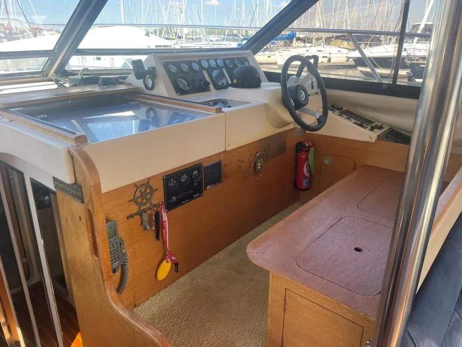 1985 Princess Sedan Flybridge boat interior with steering wheel, control panel, and wooden finish.