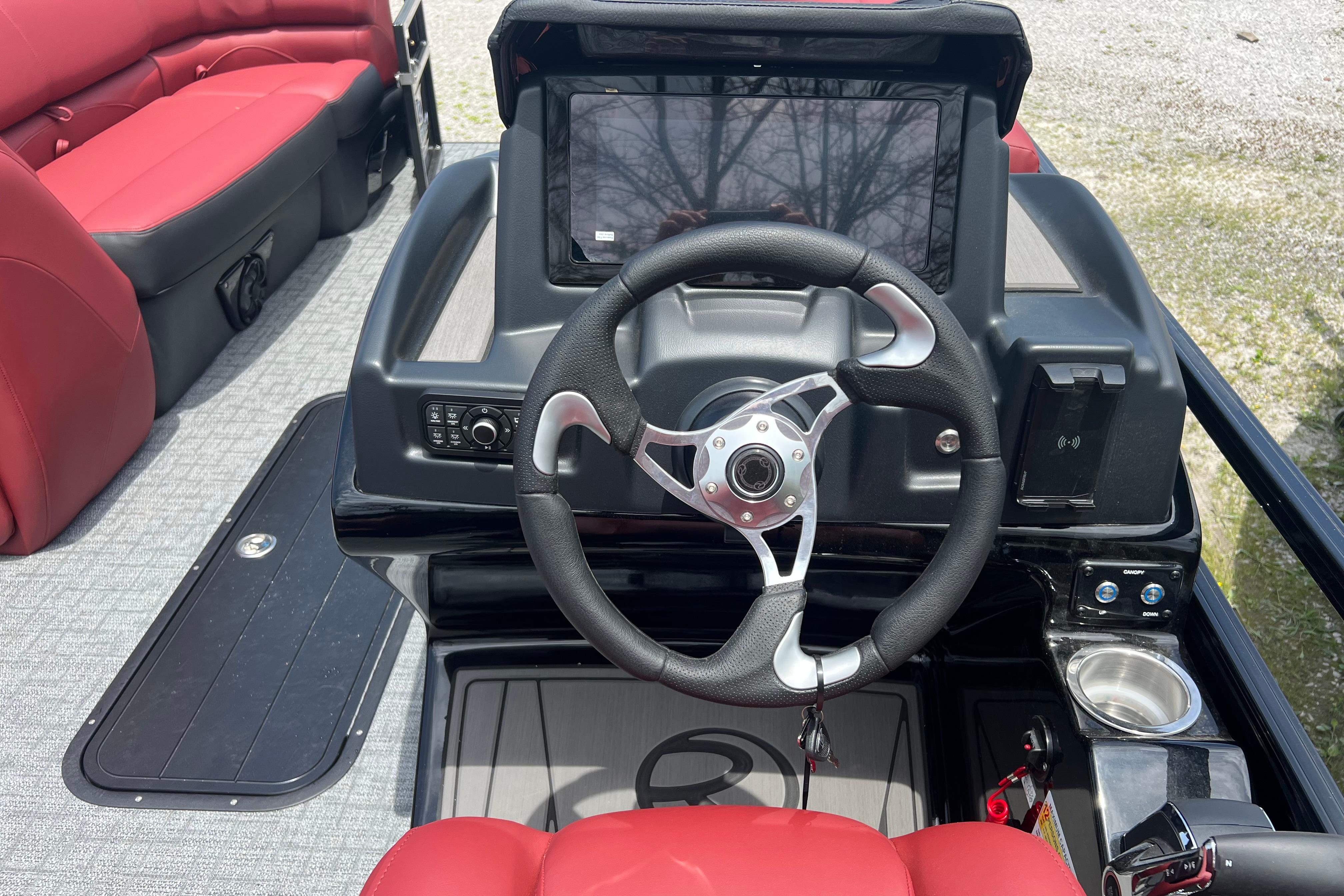 Steering console of 2026 Regency 230 DL boat with red seating and modern controls.