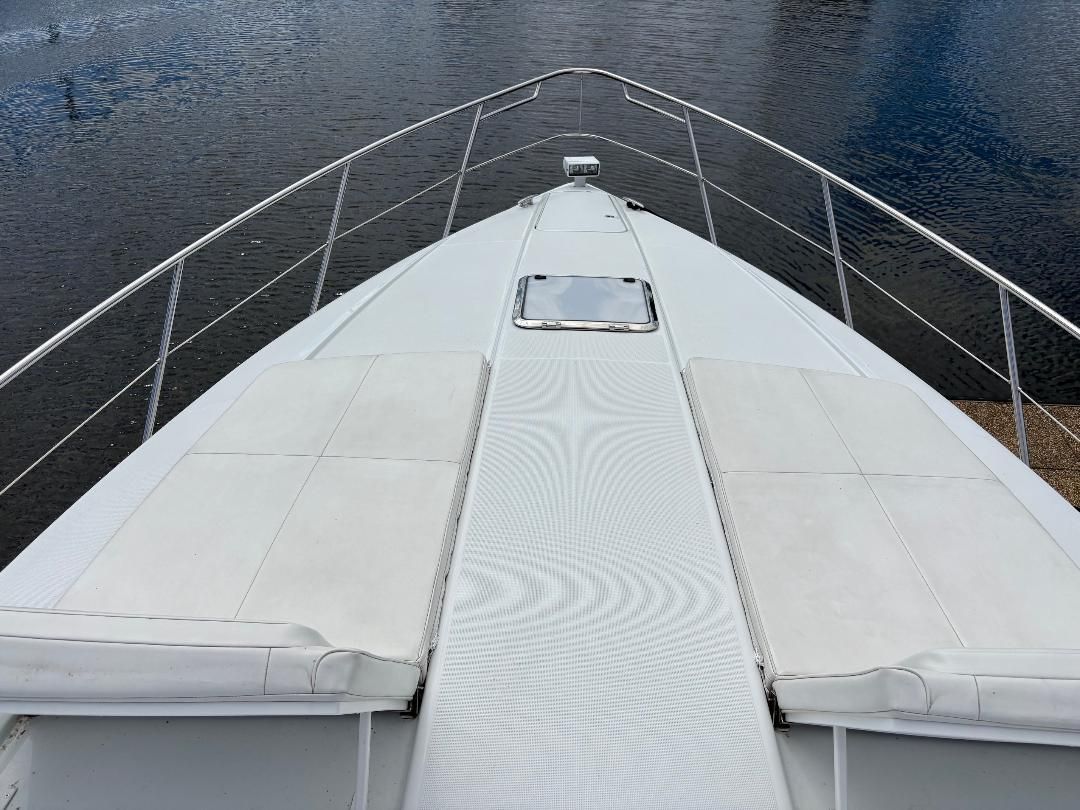 Foredeck of a 2011 Formula 45 with white cushions and stainless steel railing, on calm water.