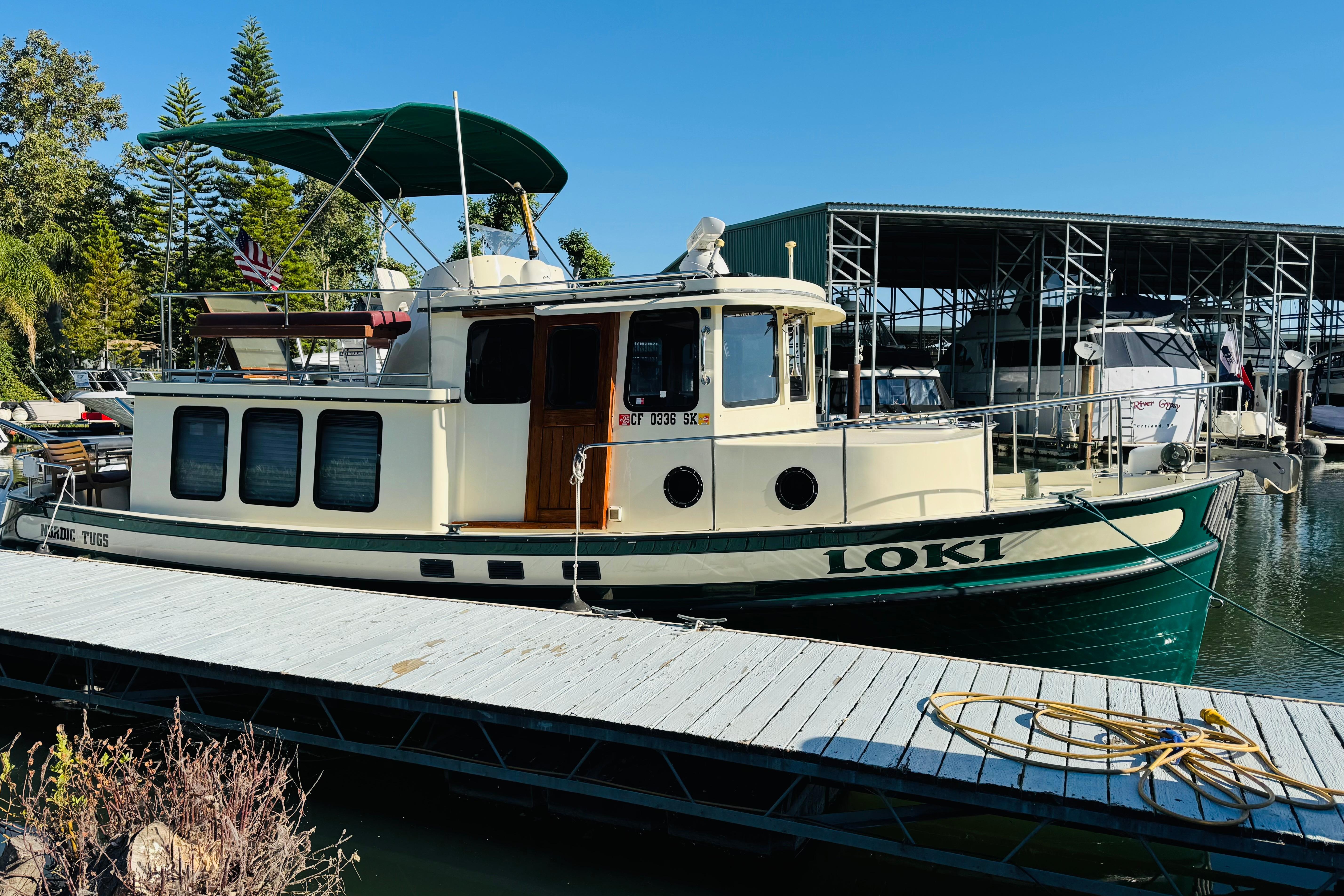 1996 Nordic Tug 32 boat named "Loki" docked at a marina under clear blue skies.