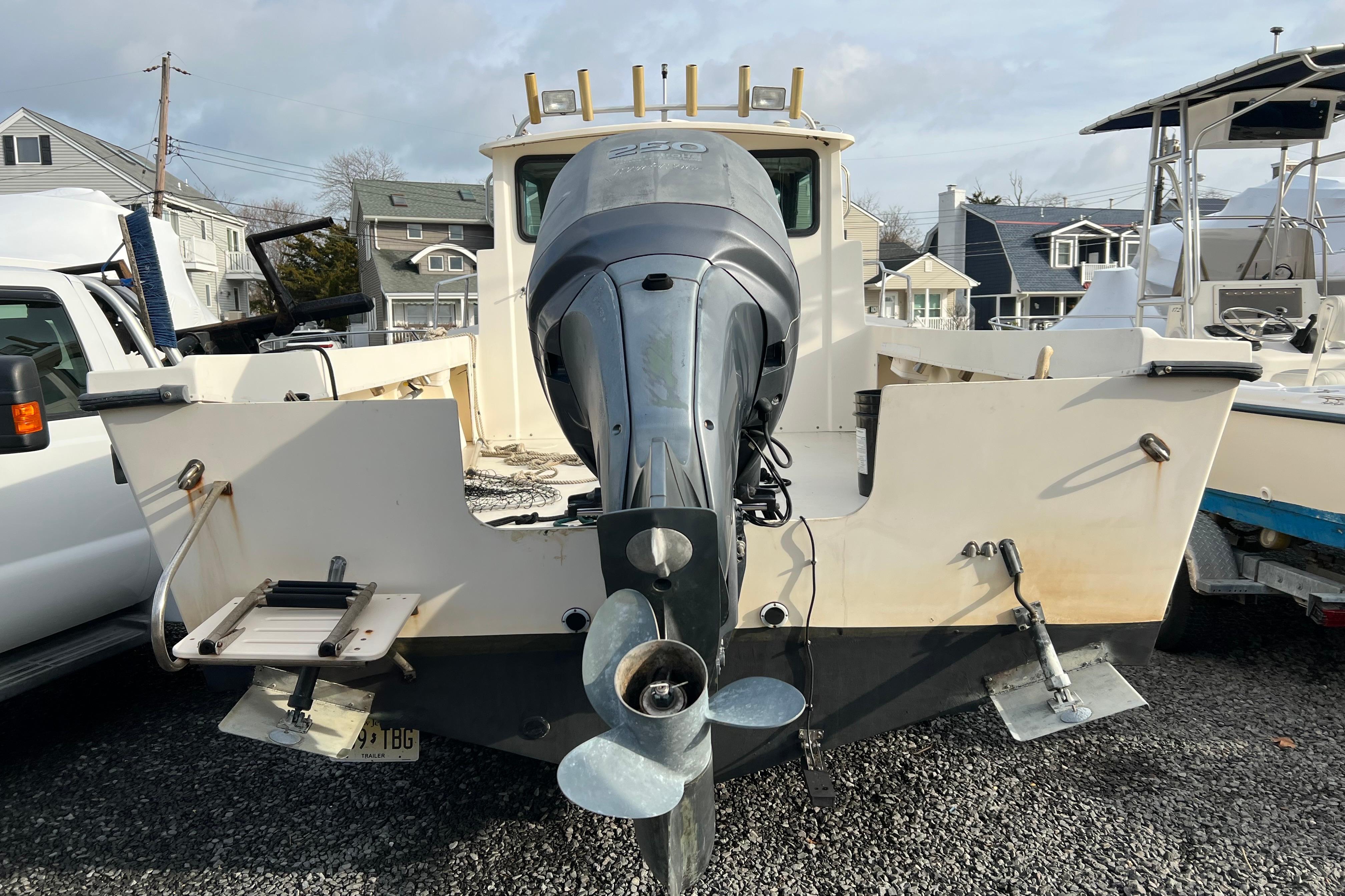 2001 Parker 2520 Deep Vee Sport Cabin boat with outboard motor, parked on gravel.