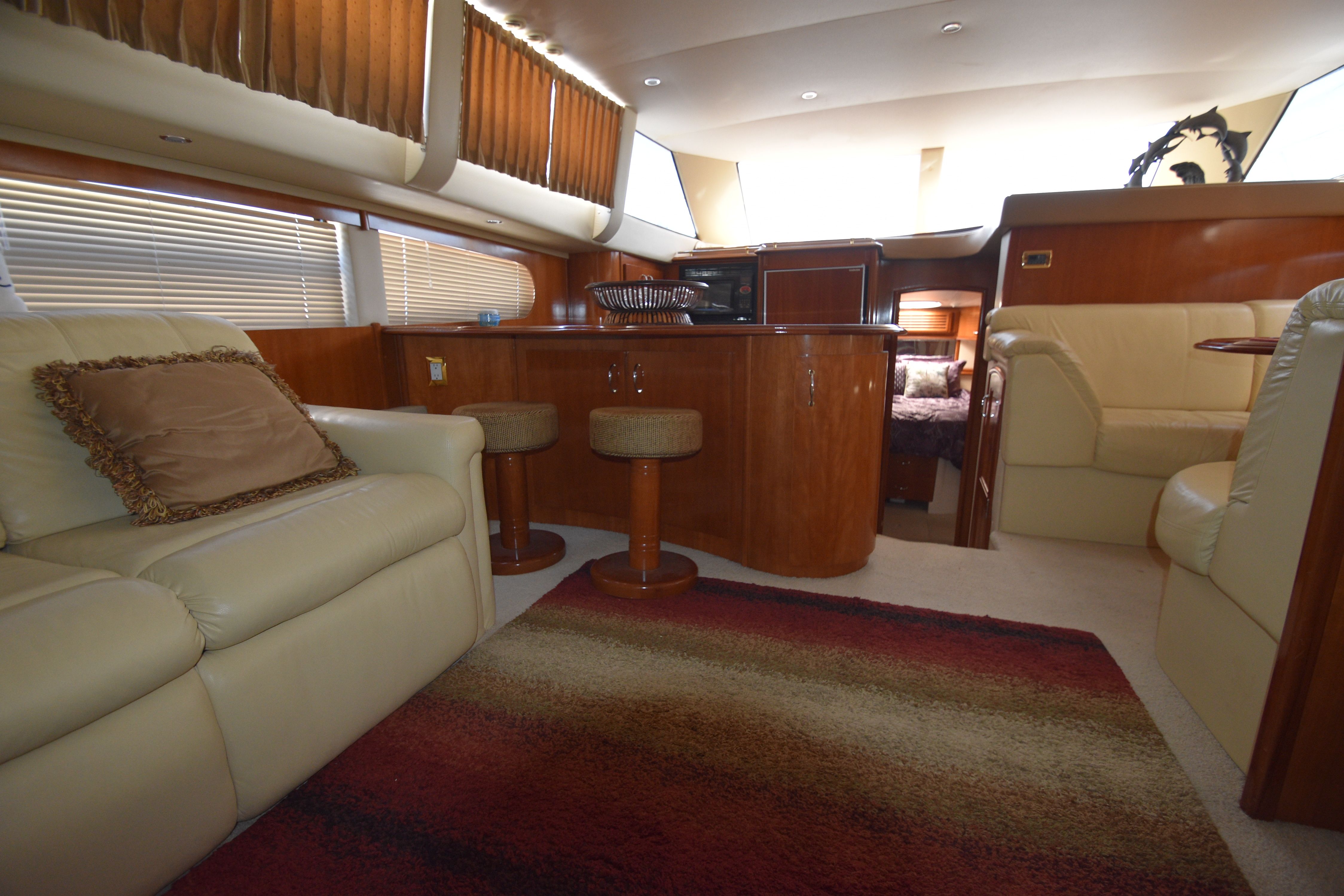 Interior of a 2004 Carver 466 Motor Yacht with beige leather sofas and wooden furnishings.