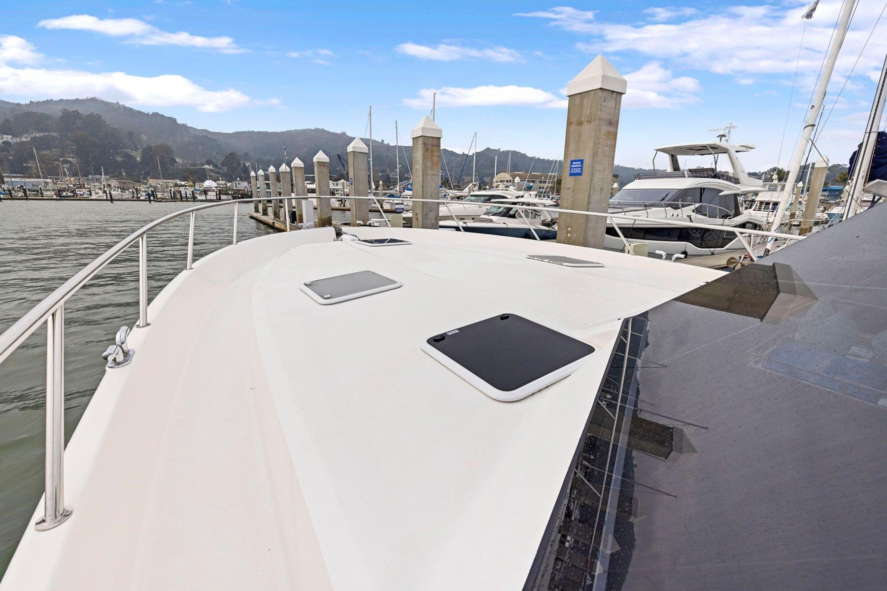 2014 Maritimo M50 yacht docked at a marina with scenic mountain backdrop.