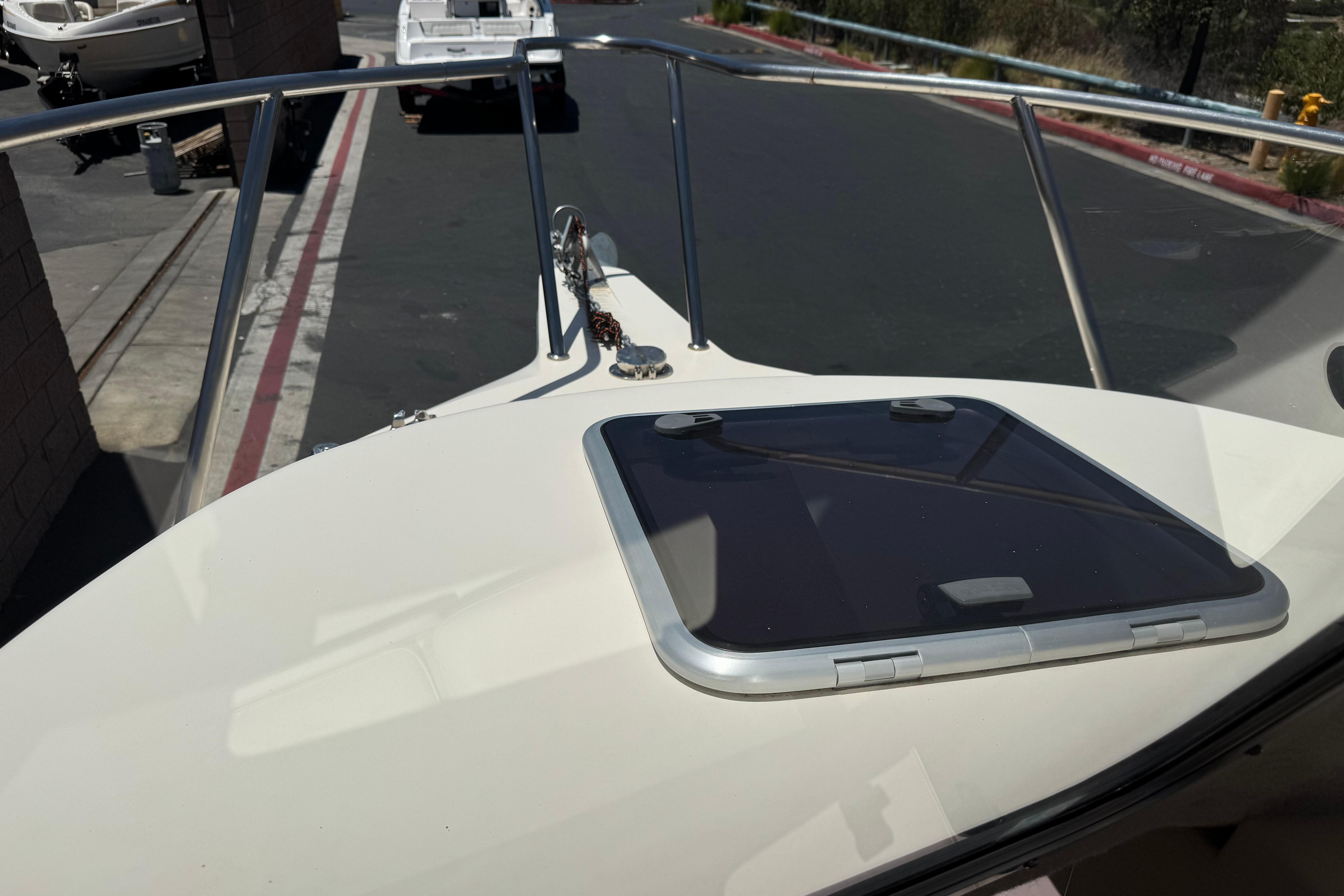 2017 Defiance Admiral 220 EX boat bow with hatch and railing in a marina setting.