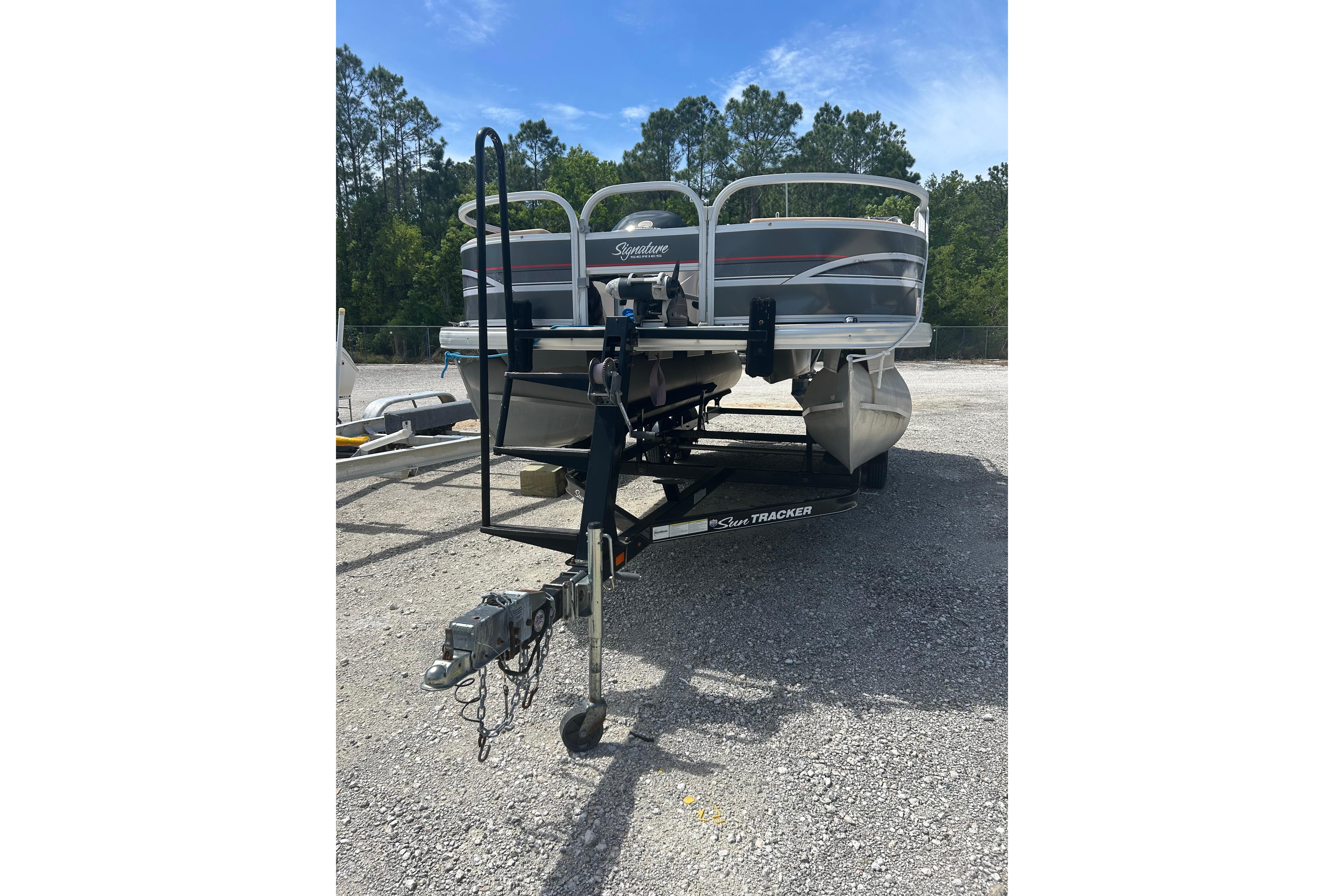 2015 Sun Tracker Party Barge 22 Tritoon on trailer in outdoor setting.