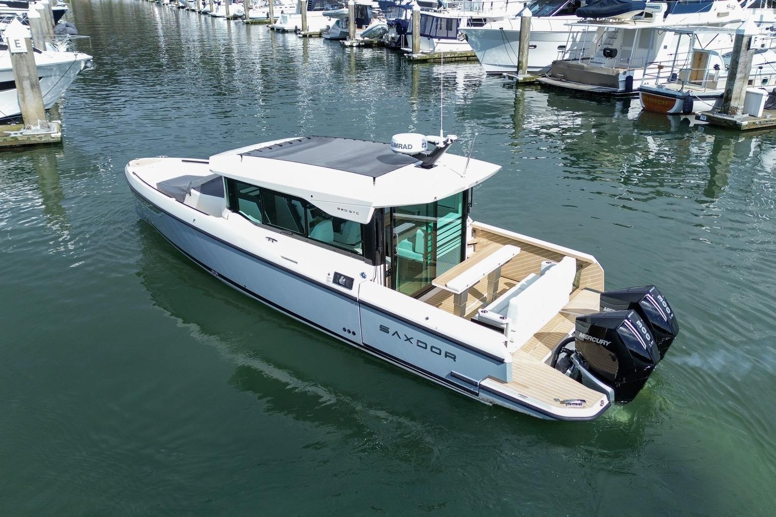 2026 Saxdor 320 GTC boat docked in marina, featuring sleek design and twin Mercury engines.