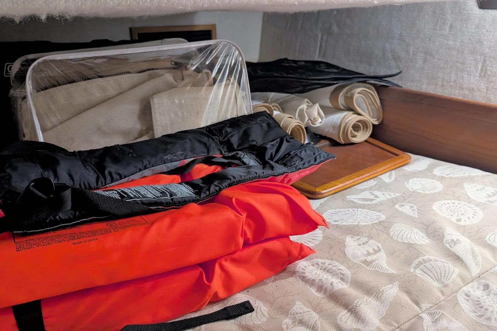 Storage area in a 2015 Ranger Tugs R-29 S with life jackets and rolled canvas.