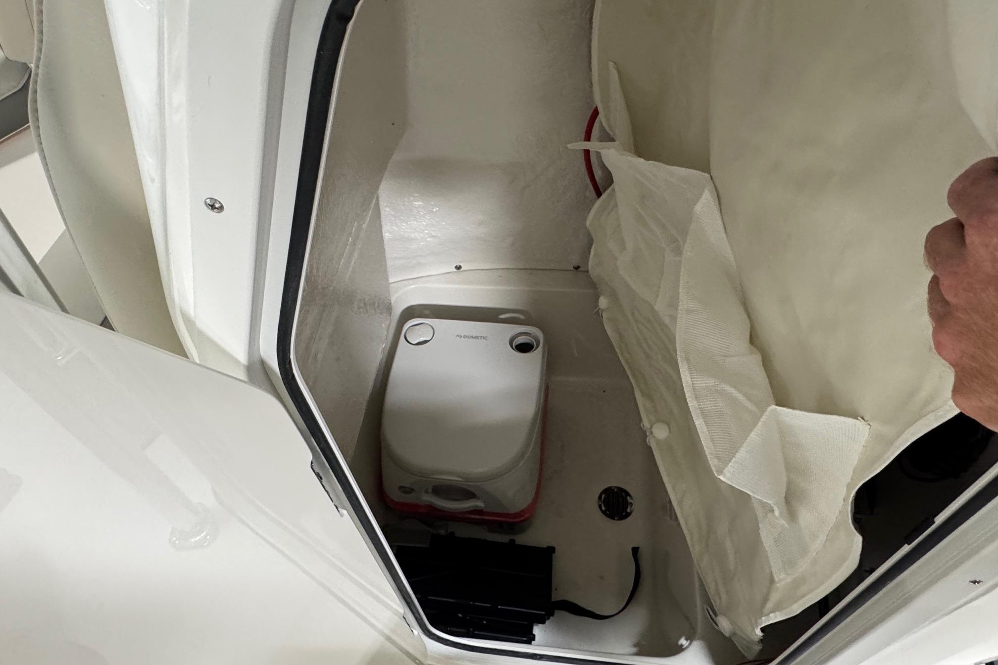 Interior of 2026 Key West 203 FS boat showing storage compartment with portable toilet.