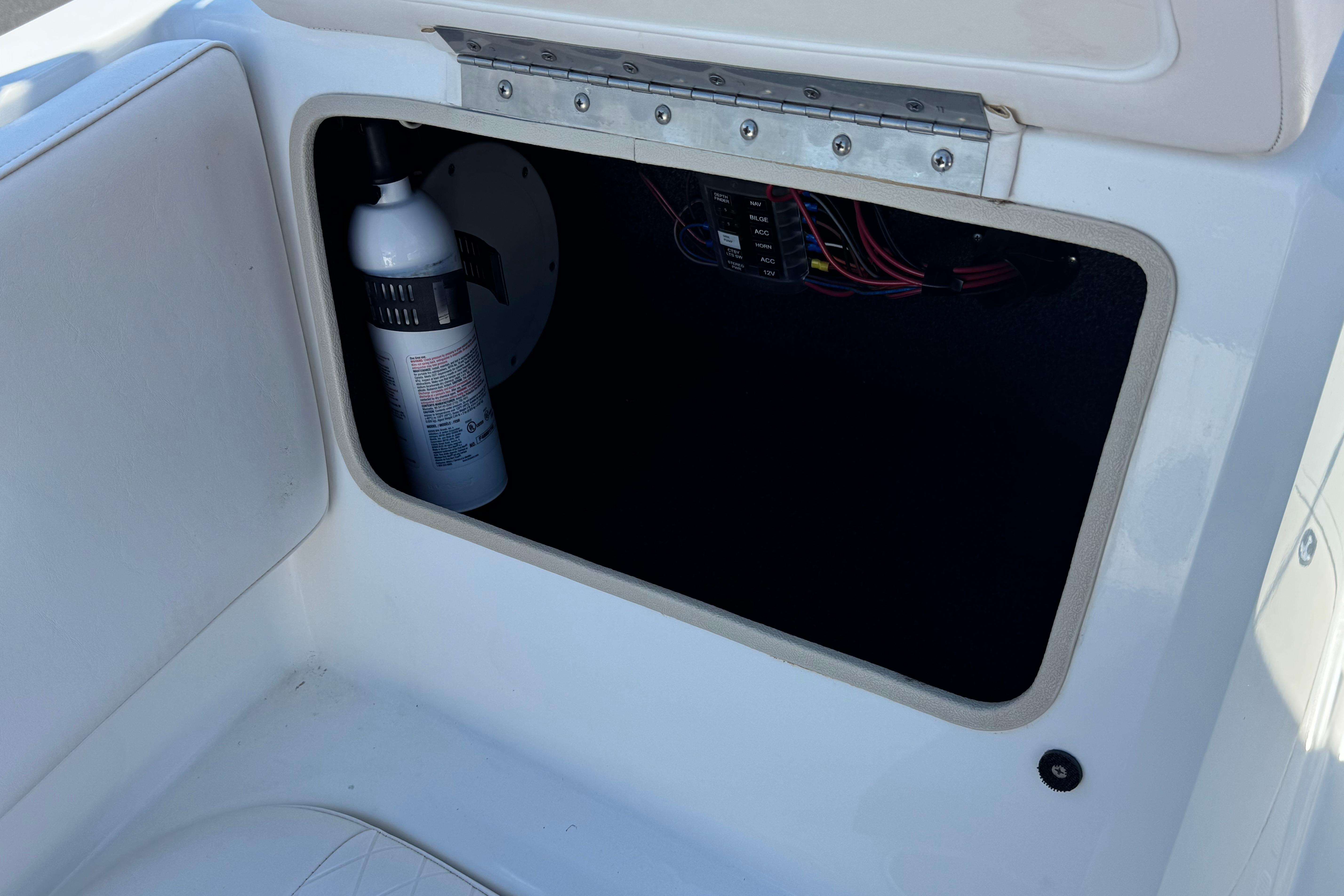 Storage compartment in a 2019 Tahoe 2150 boat, featuring a fire extinguisher and wiring.