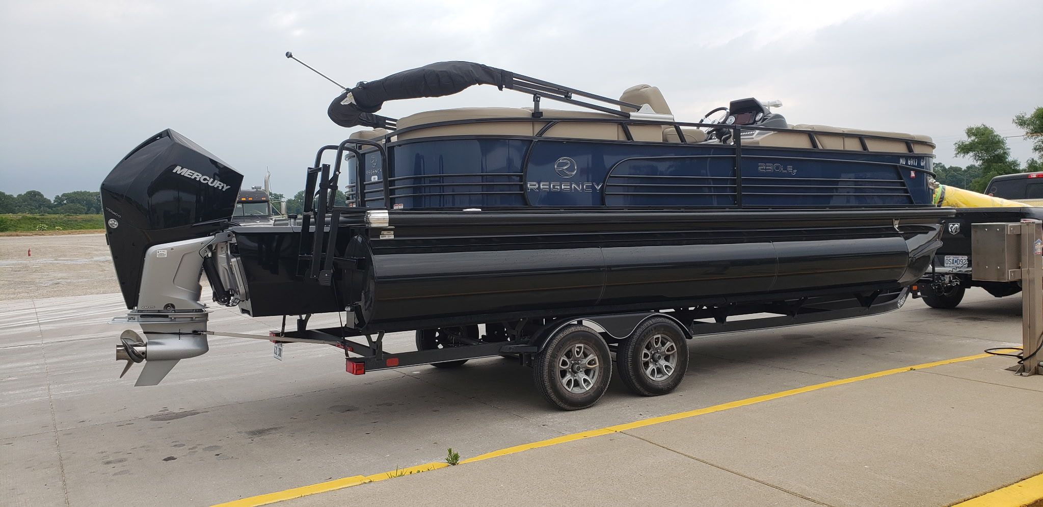 A 2021 Regency 230 LE3 pontoon boat on a trailer, parked on land.