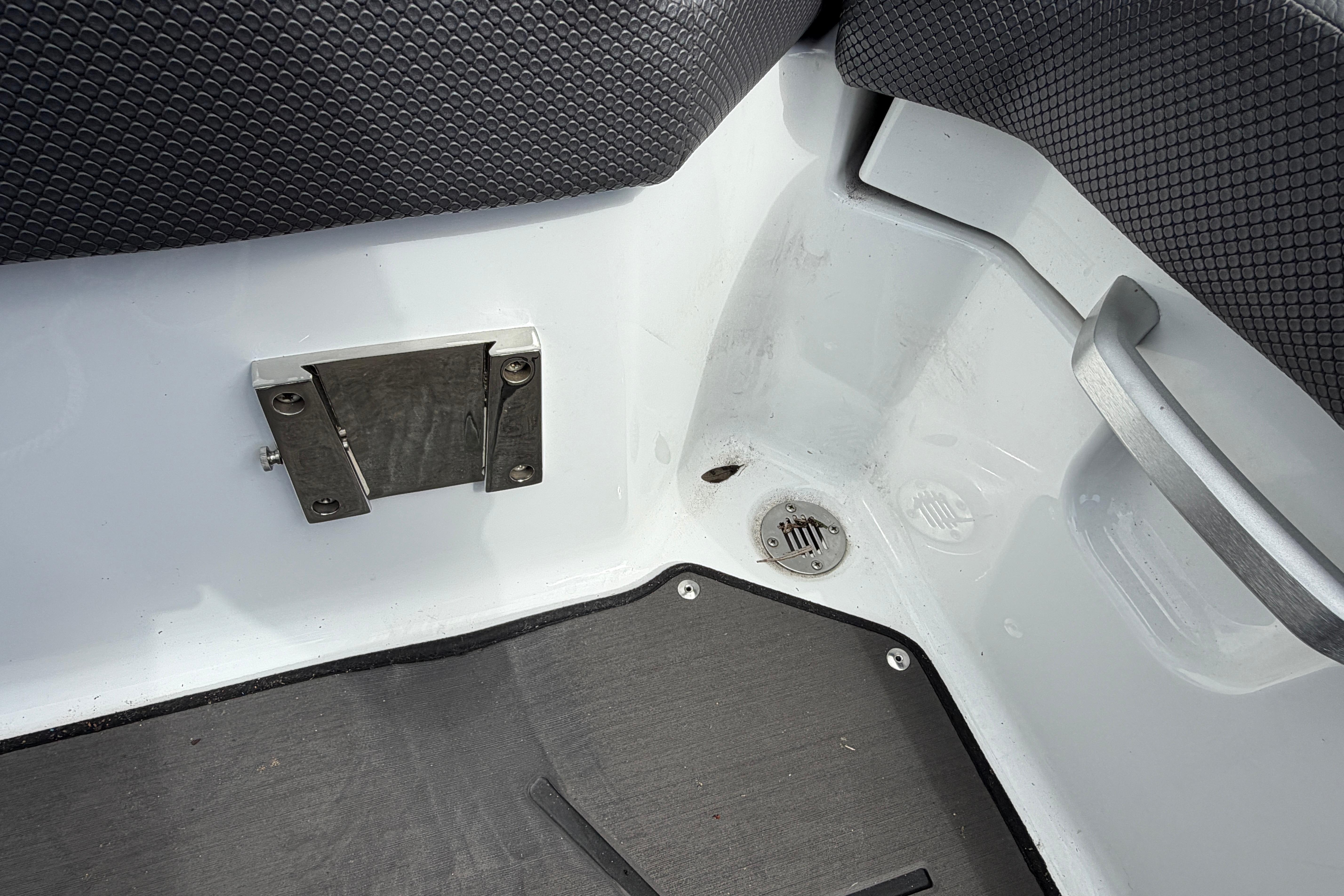 Interior corner of 2026 Scarab 235 LX boat, featuring drain and metal fixtures.