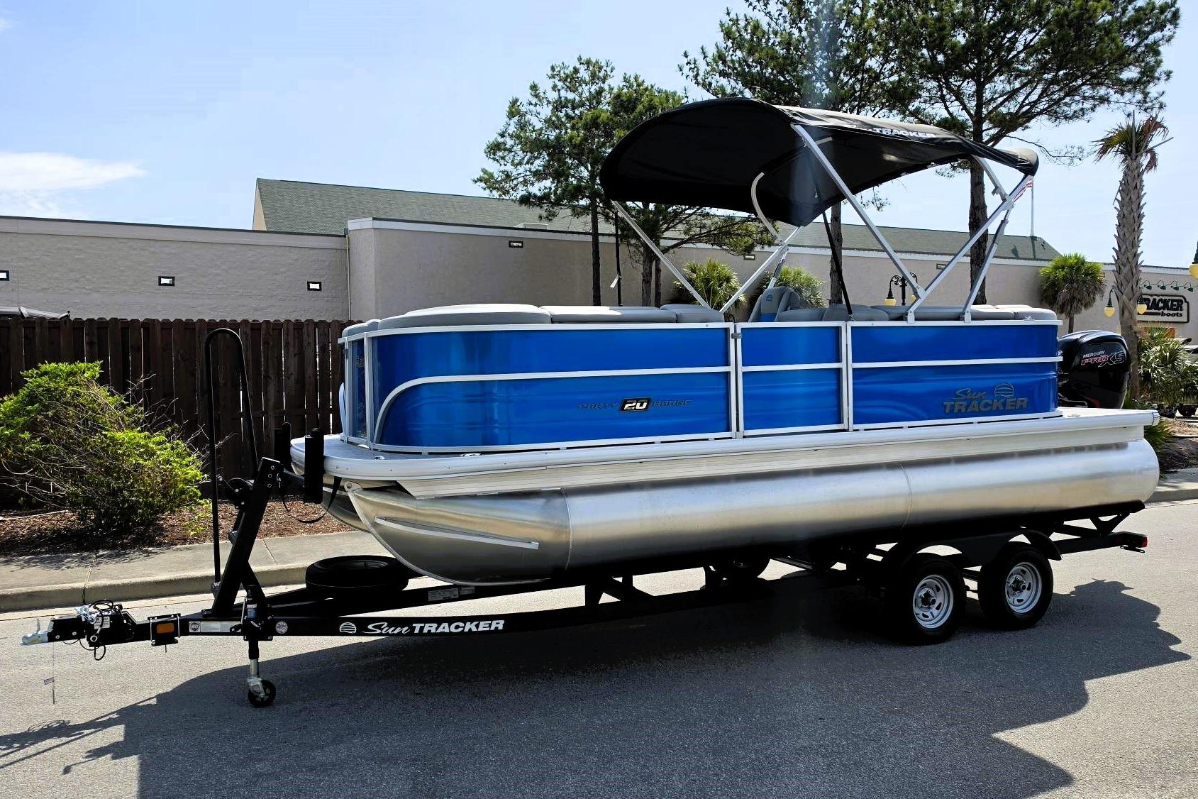 2026 Sun Tracker Party Barge 20 DLX pontoon boat on trailer, parked outdoors.