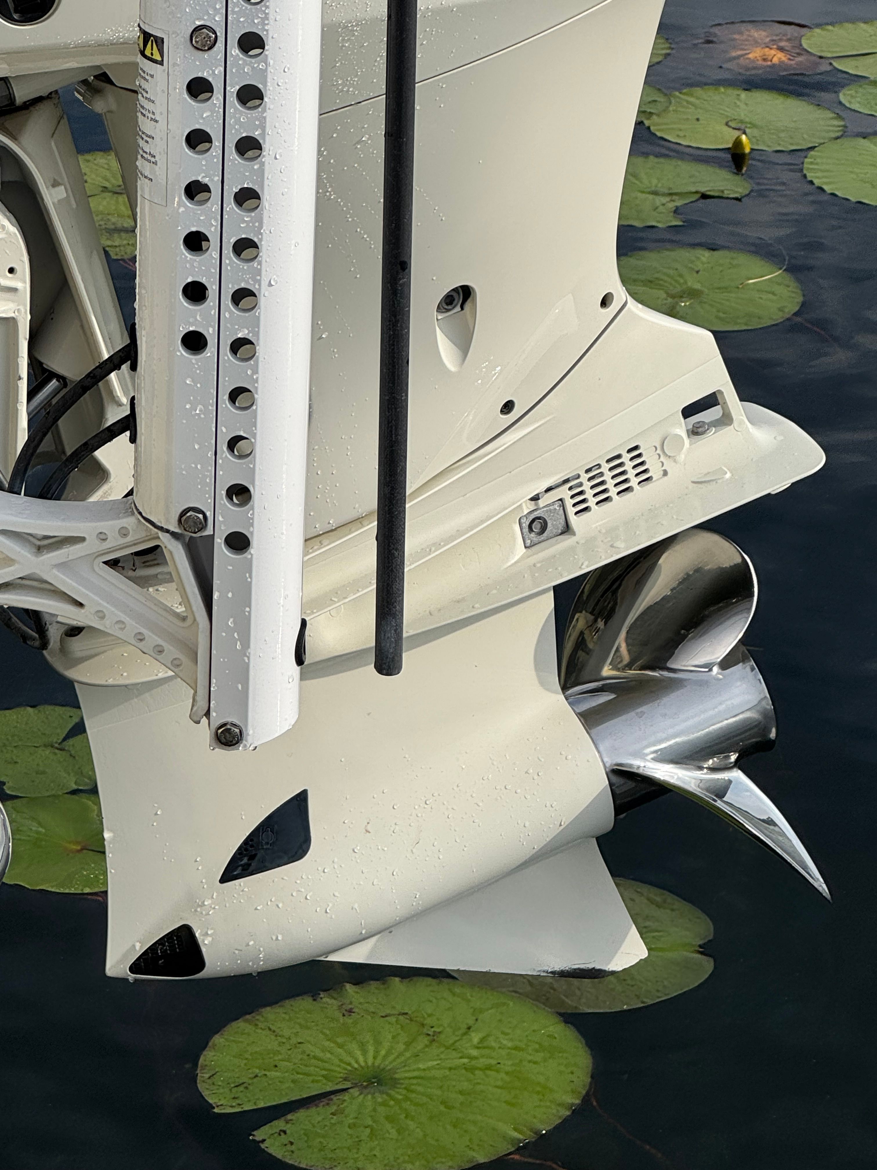 Outboard motor of a 2004 ShearWater LTZ above lily pads.