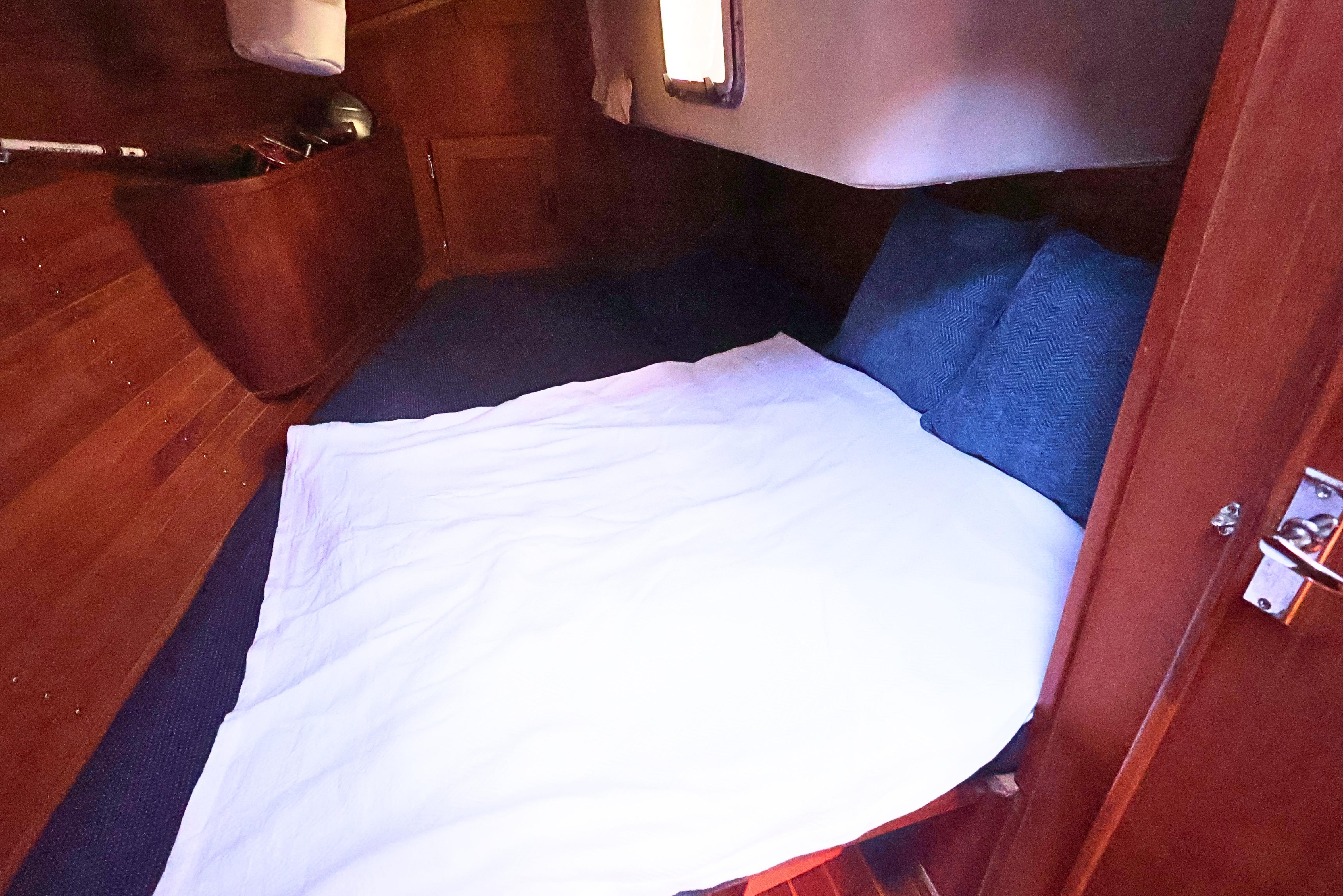 Cozy cabin interior of 1989 J Boat J 40 with wooden finish and bedding.