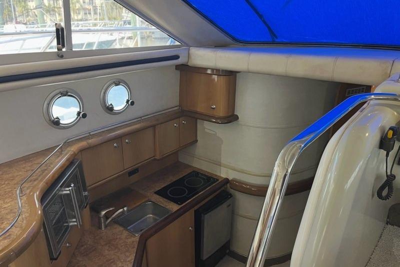 Interior of a 1999 Sealine F44 yacht featuring a compact kitchen with porthole windows.
