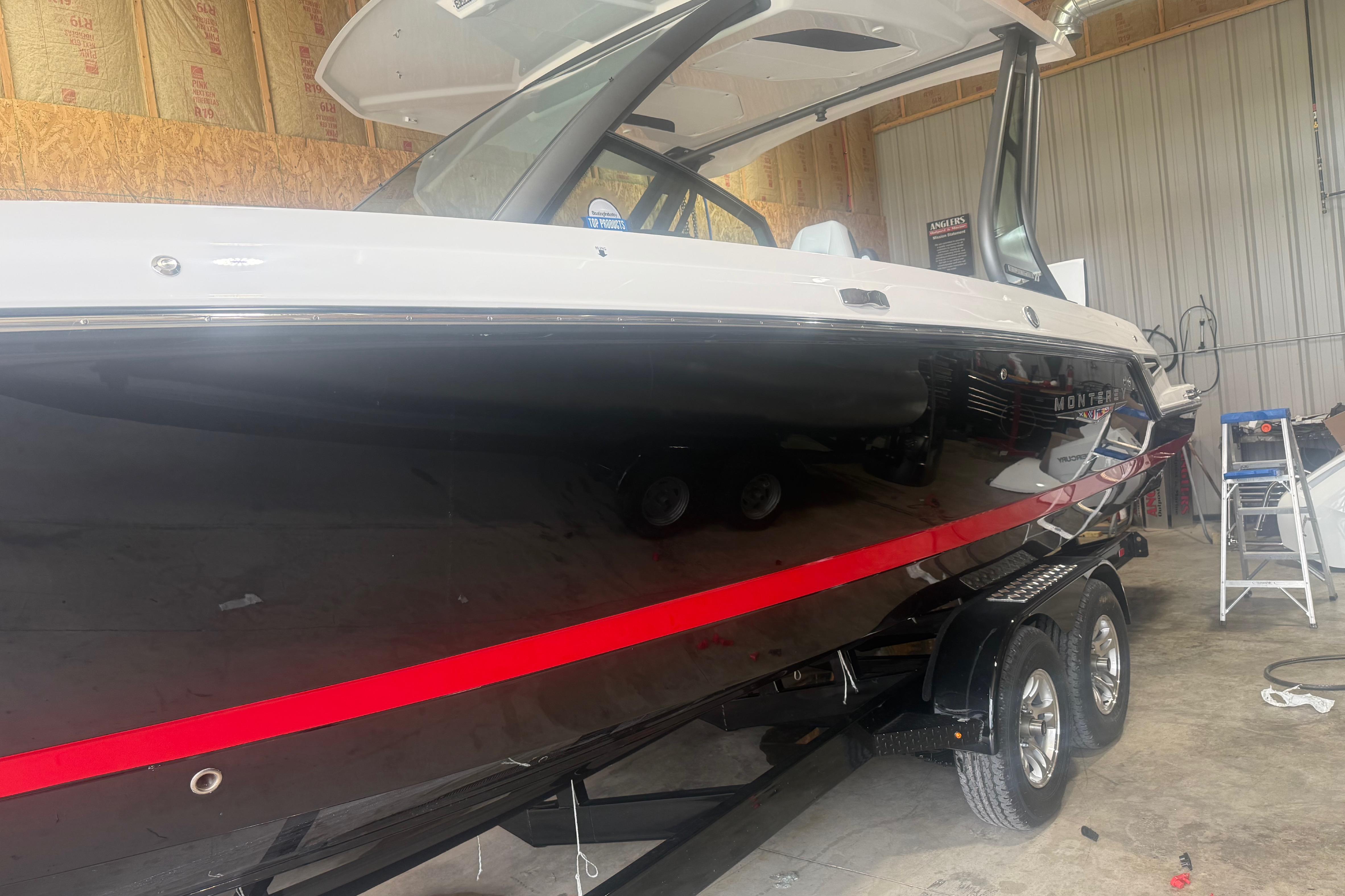 2027 Monterey Elite 27 SD boat in a garage, featuring sleek black and red design.