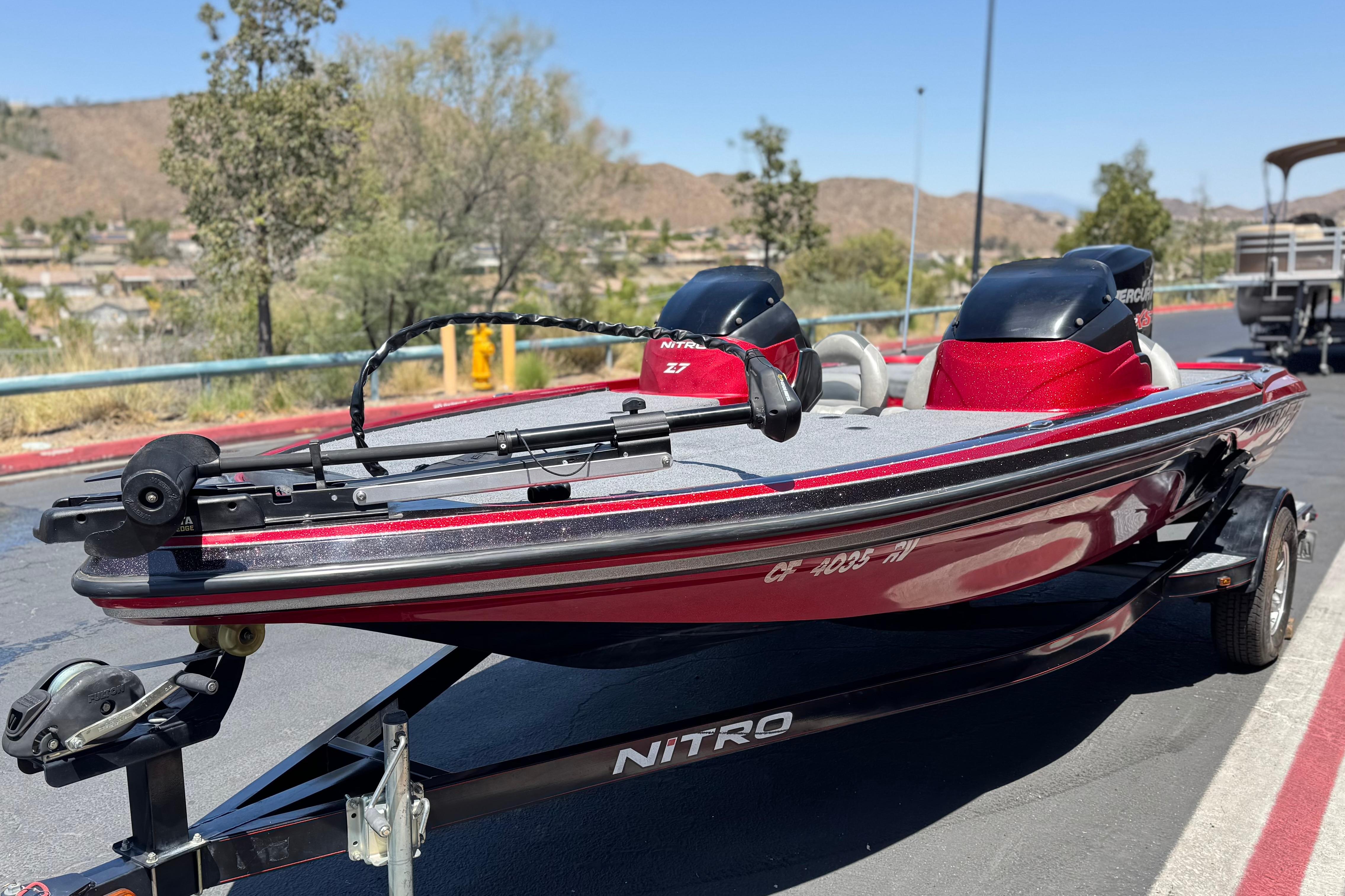 2012 Nitro Z-7 bass boat on trailer, red and gray, parked outdoors.