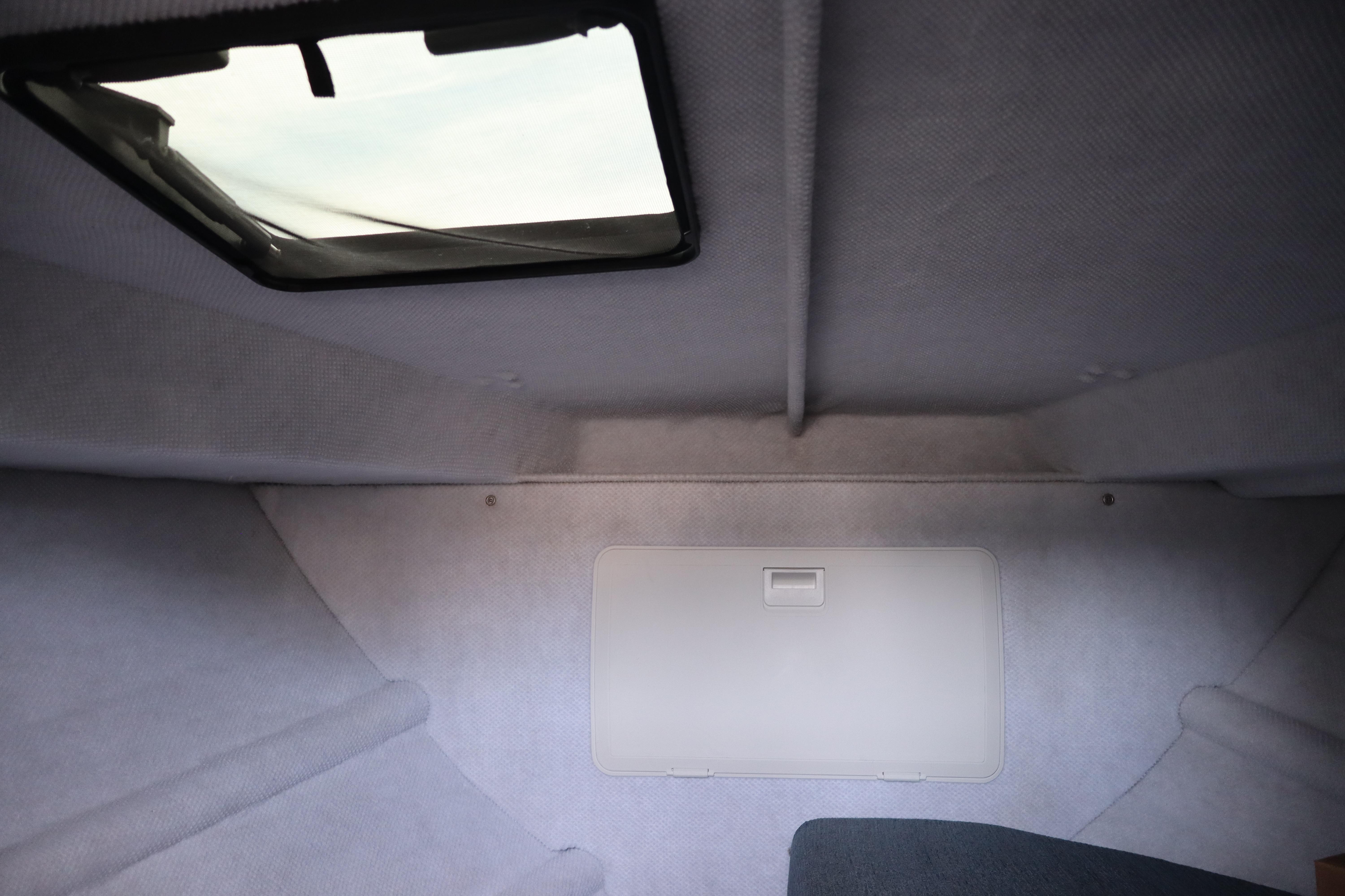 Interior cabin of 2026 KingFisher 25 XAC boat with skylight and storage compartment.