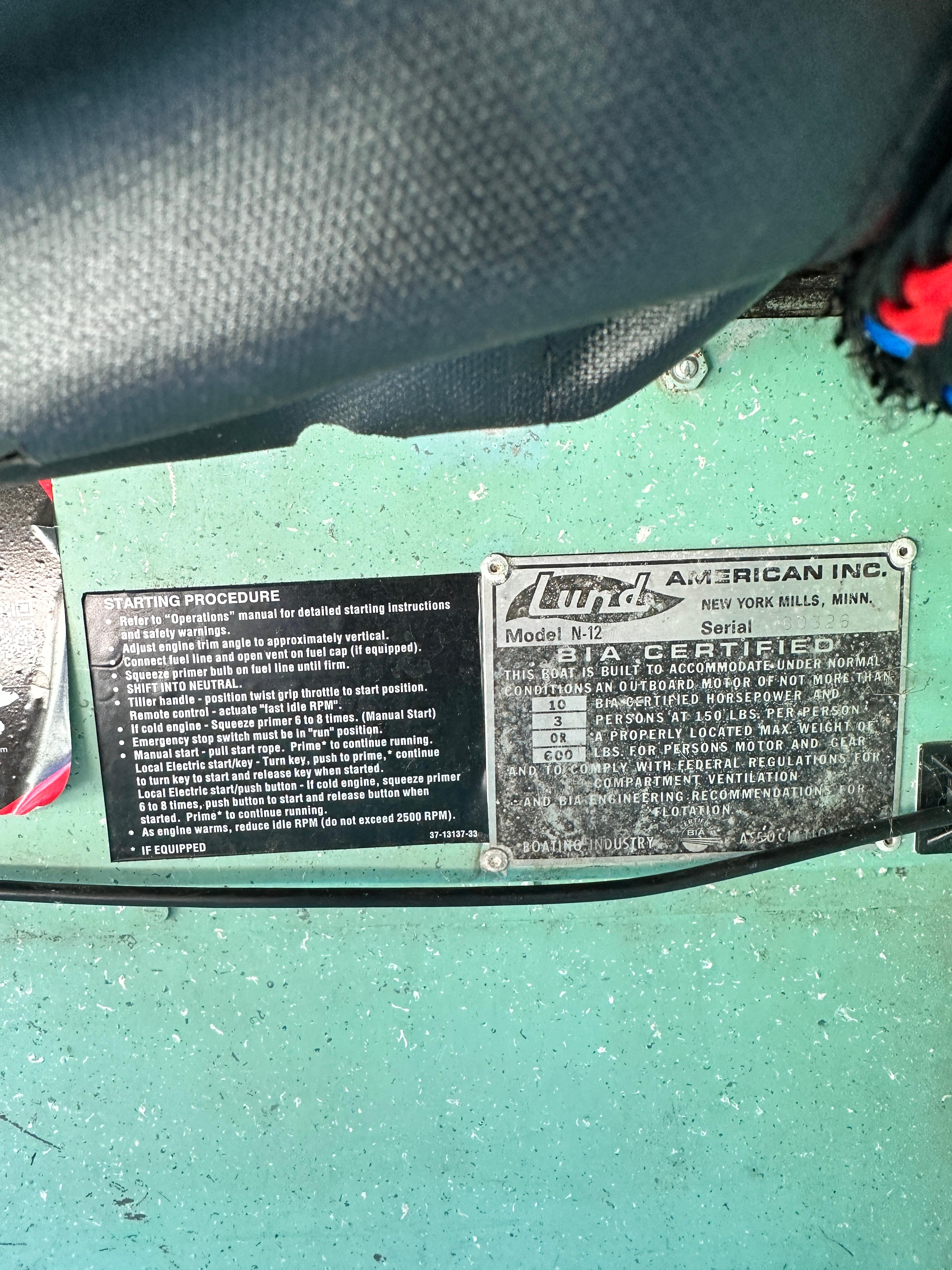 1960 Lund H boat certification and starting procedure labels on green surface.
