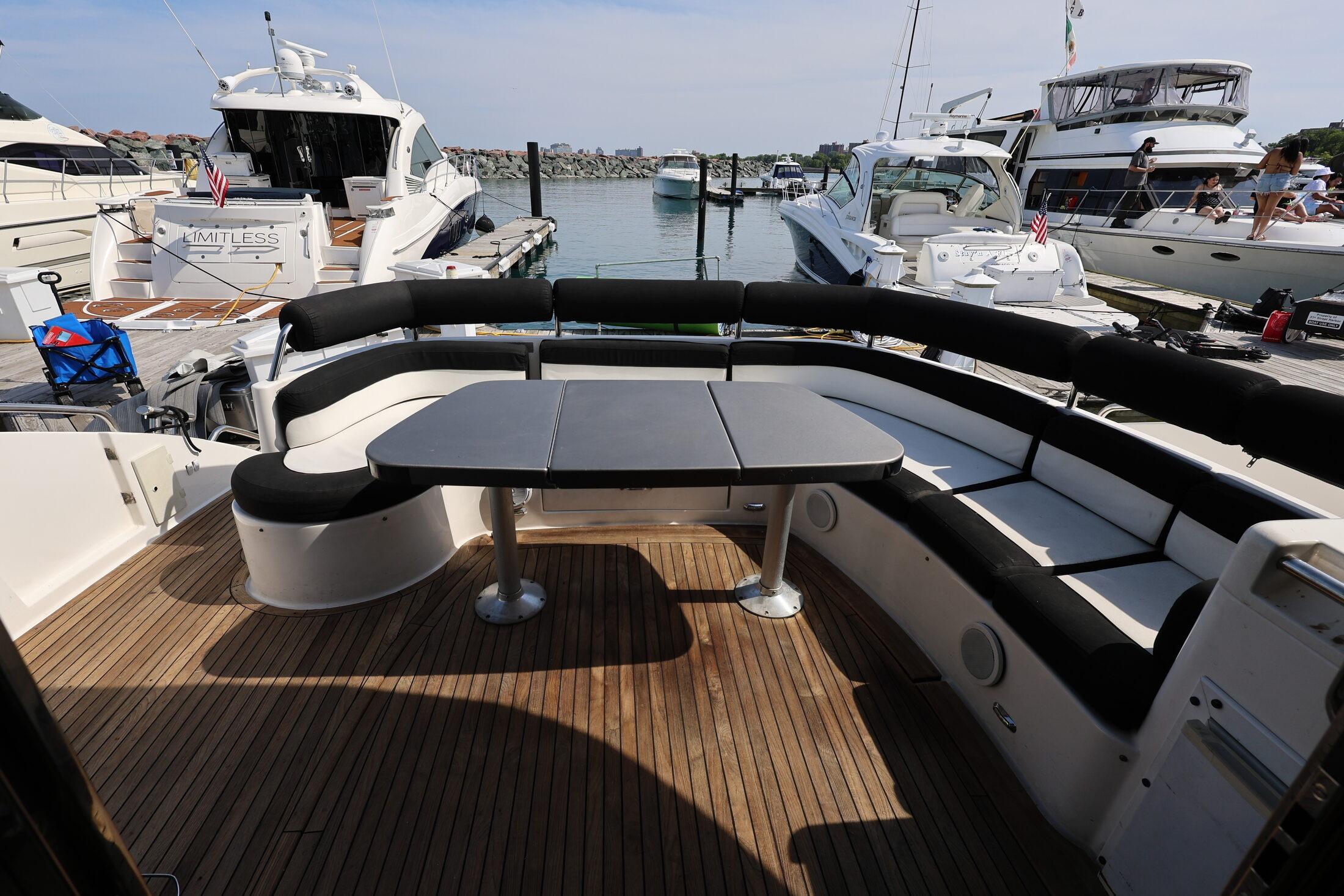 1999 Neptunus 54 Express yacht with spacious deck seating and table, docked at marina.