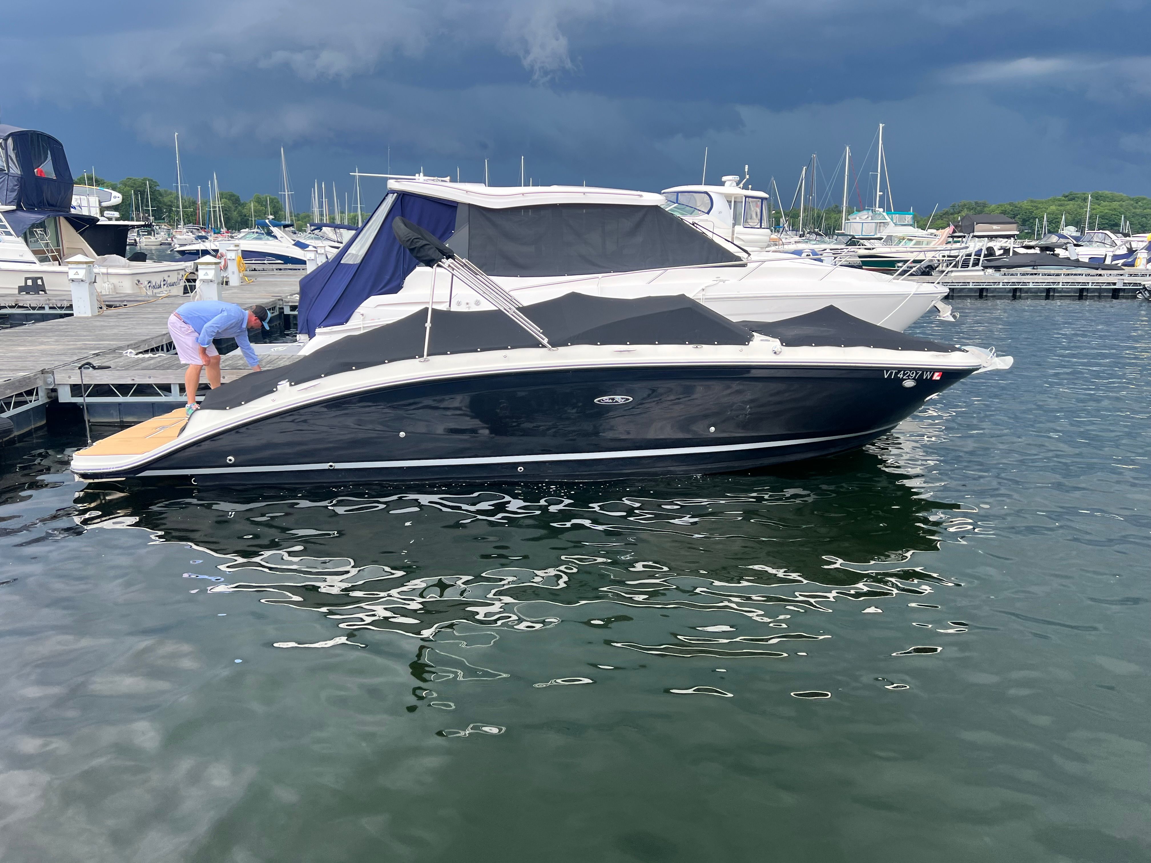 2018 Sea Ray SDX 270 boat docked in harbor under cloudy sky.
