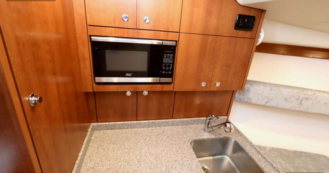 Interior of the 2024 Albemarle 30 Express with a microwave and sink in a wooden kitchen.