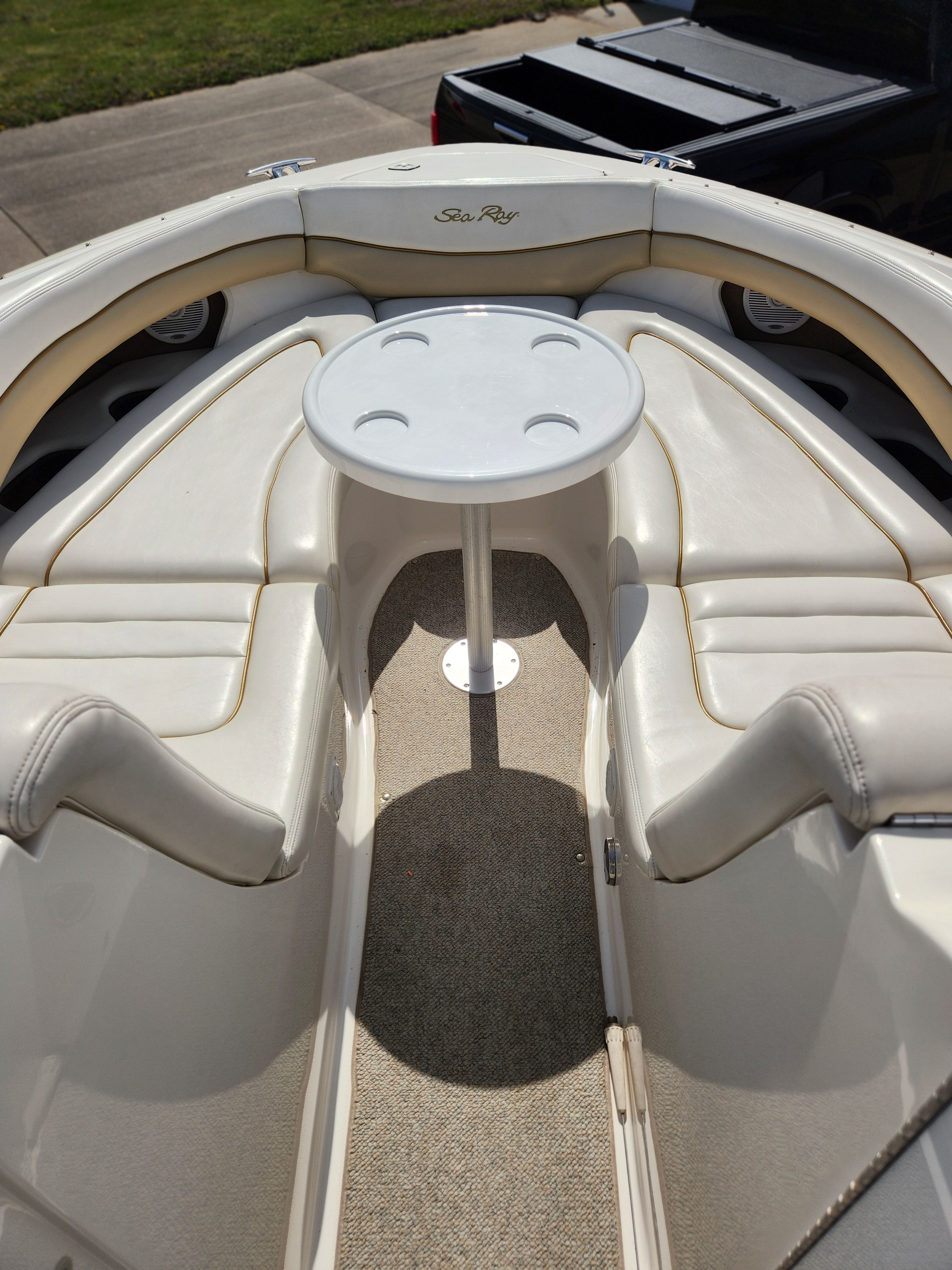 The boat features white cushioned seats and a round table in the center.