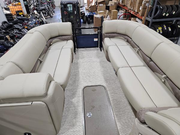 2024 Regency 250 DL3 pontoon boat interior with beige seating in a showroom.