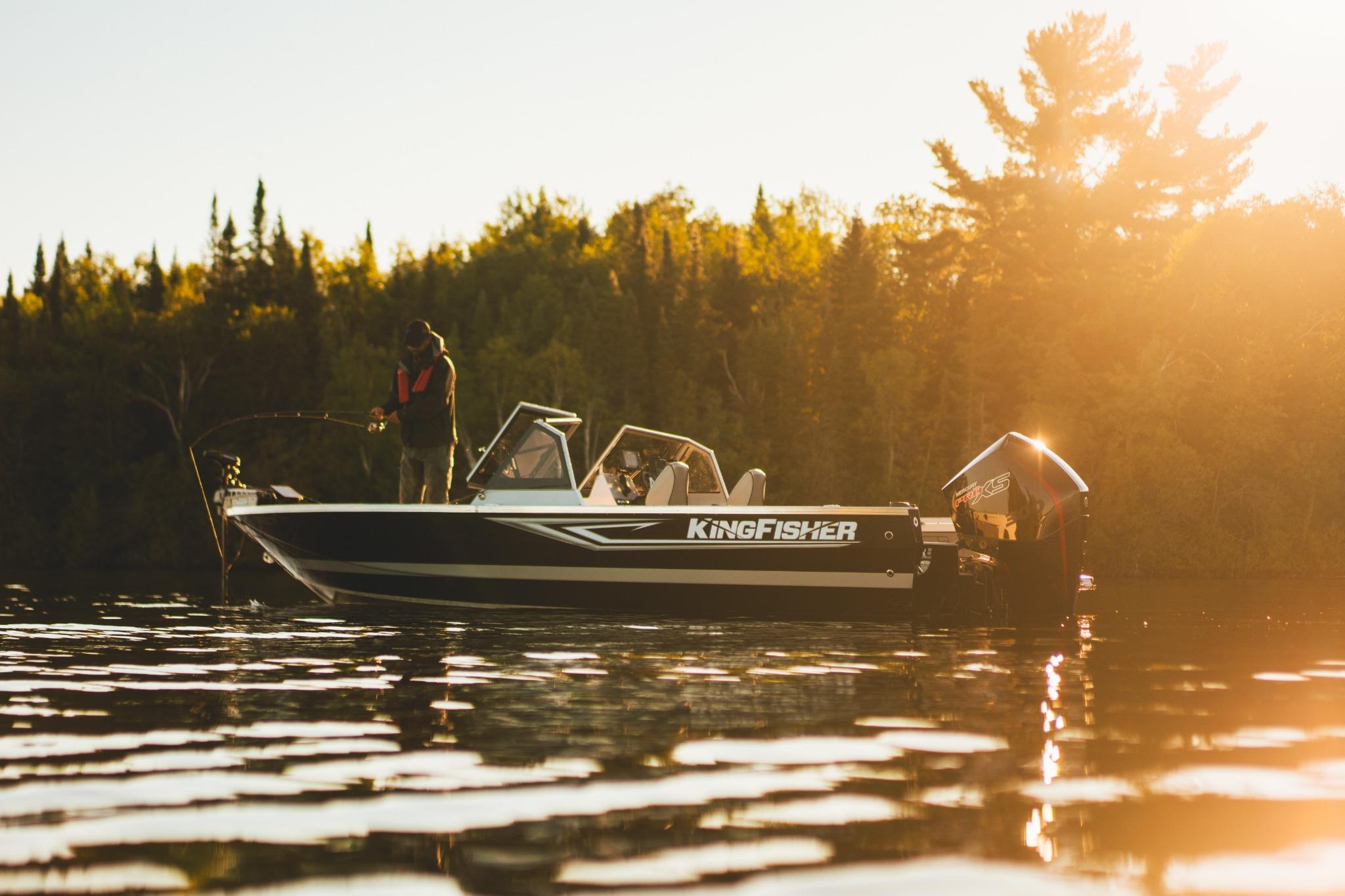 2026 KingFisher 2125 Arrow Sport boat on serene lake at sunset, person fishing.