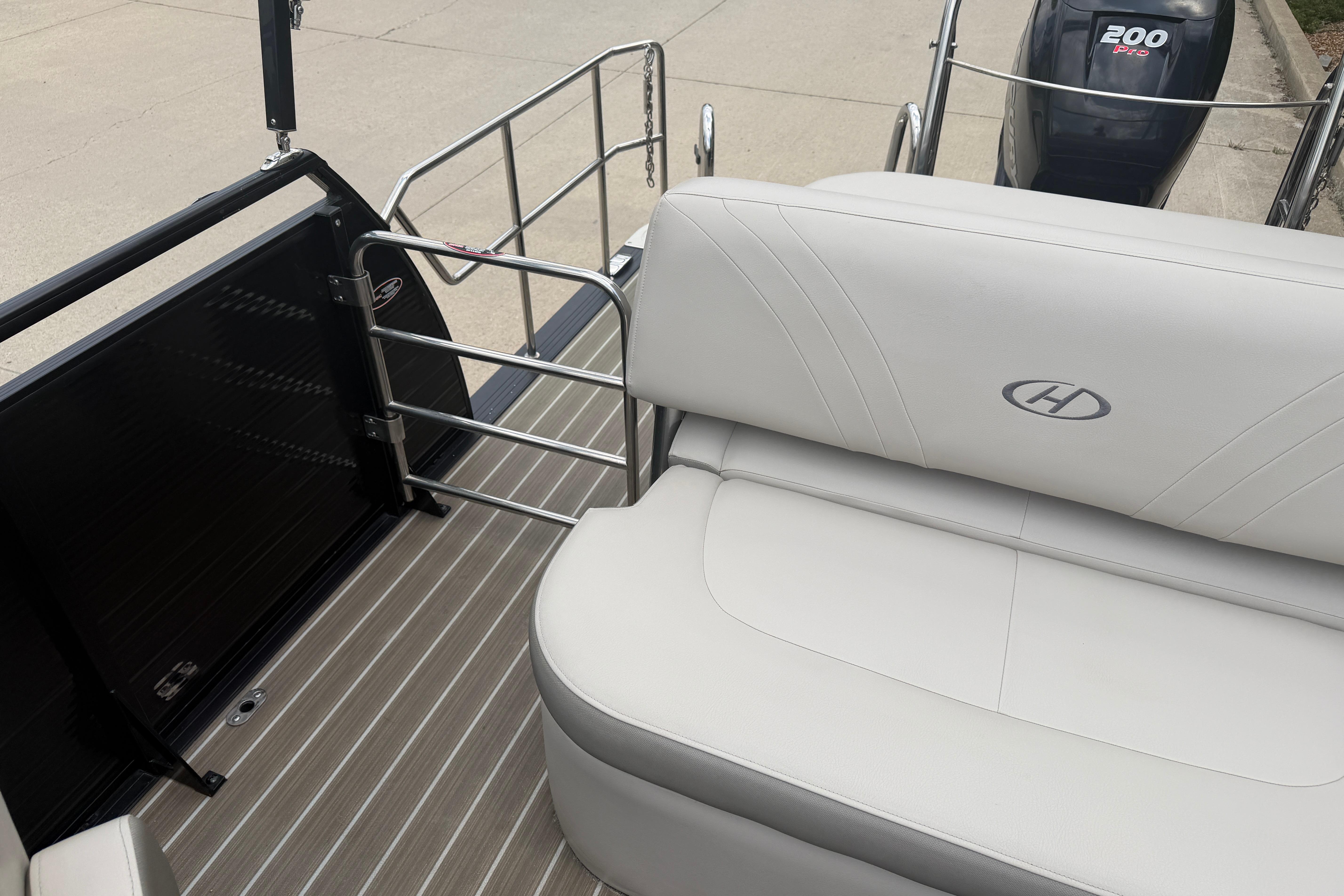 2019 Harris Solstice 240 boat interior with white seating and outboard motor.