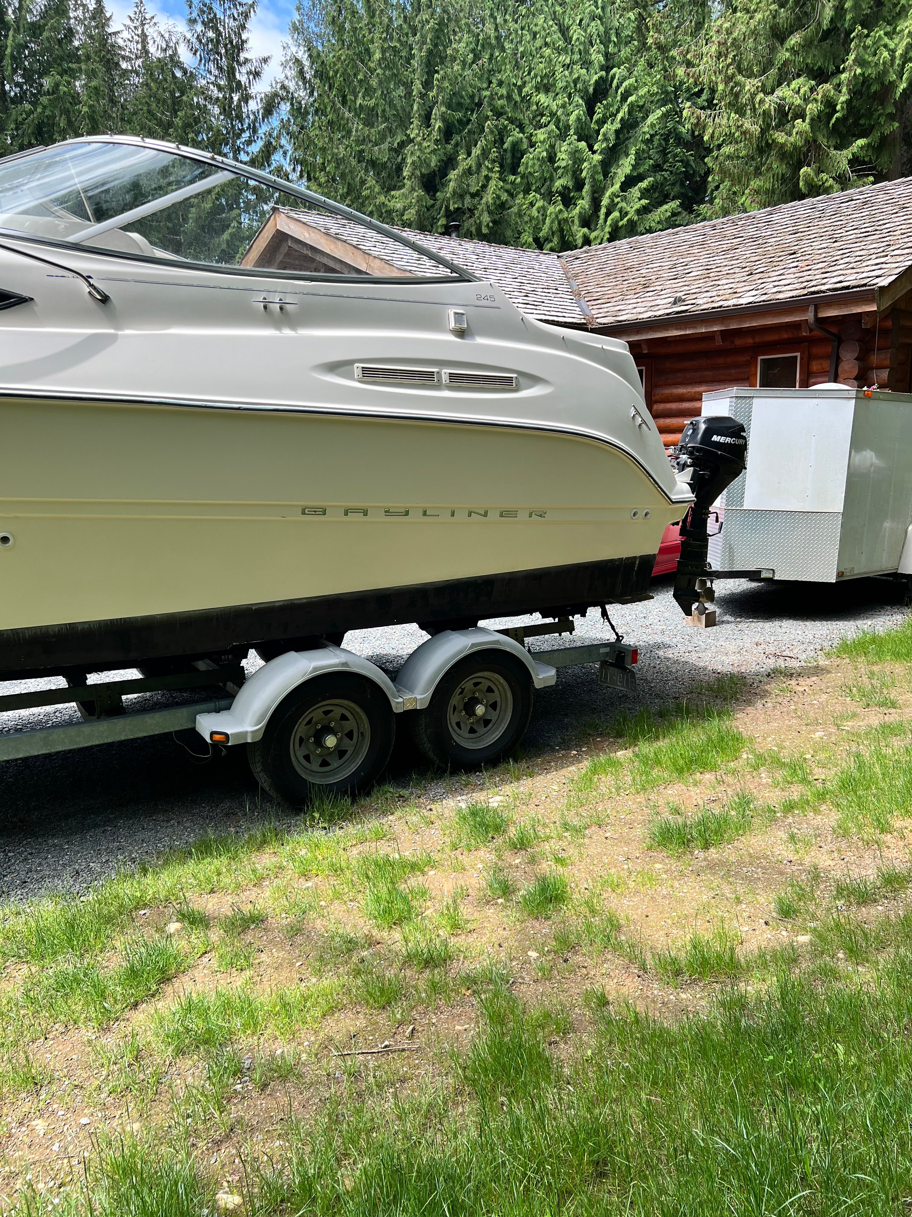 2005 Bayliner Cierra 245 on trailer in a grassy area.