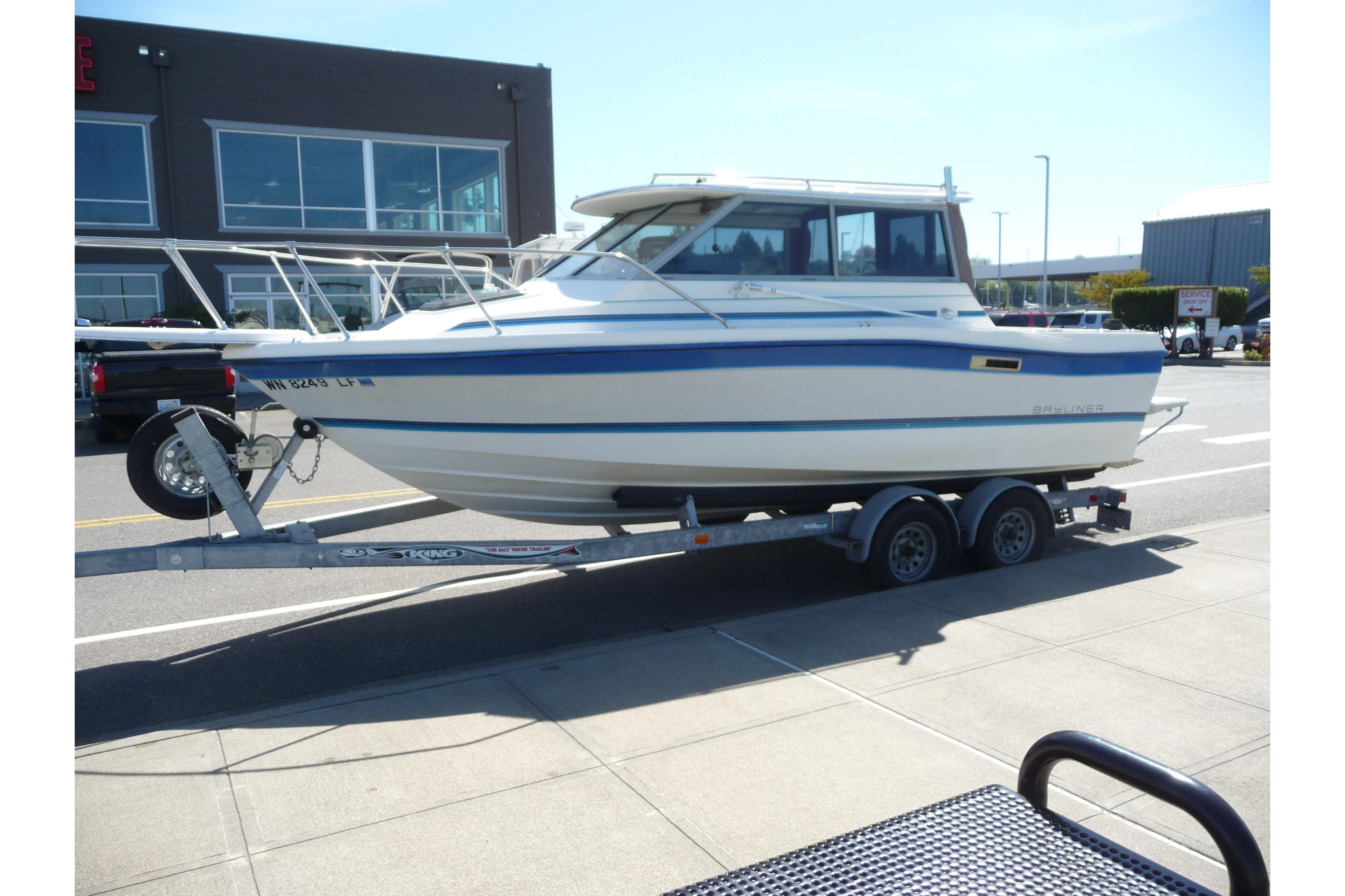 1988 Bayliner 2102 Trophy boat on trailer, parked in urban setting.