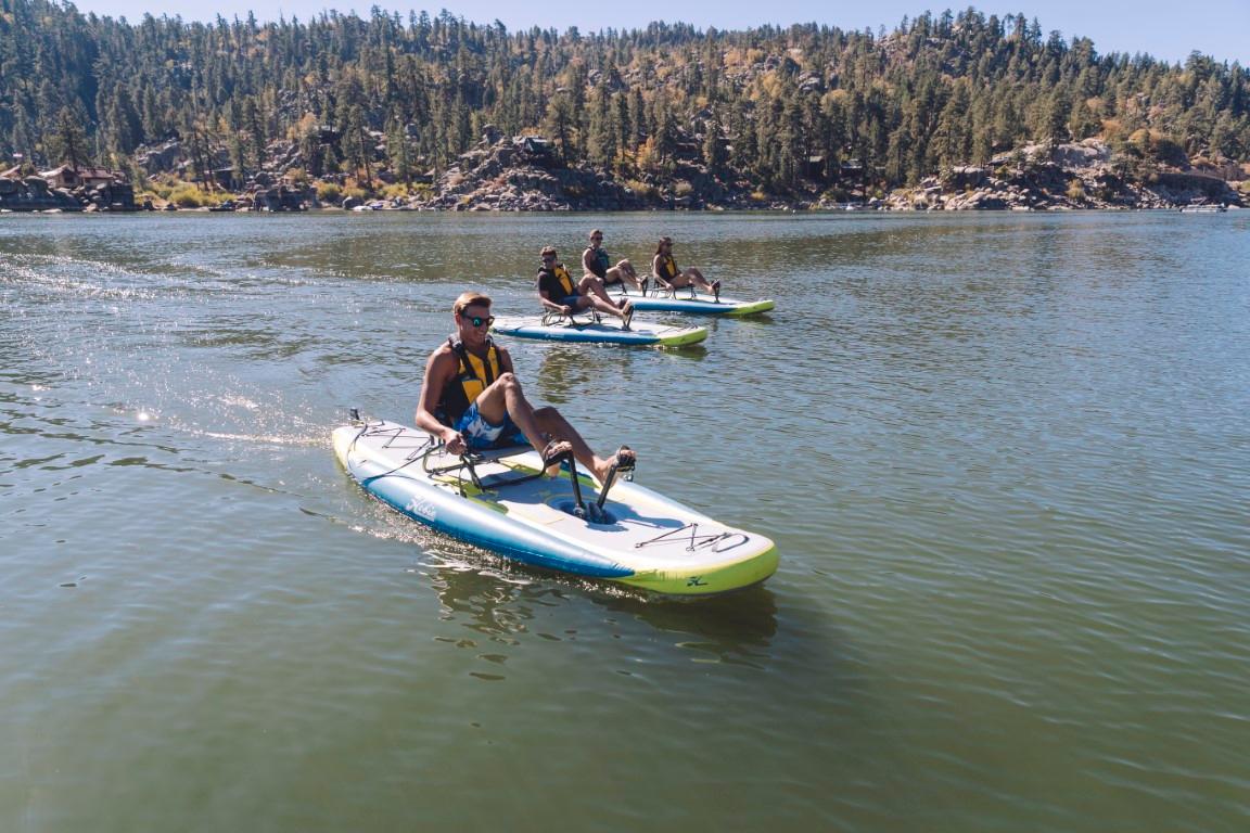 People enjoying pedal kayaking on Hobie ITREK 11 boards, 2025 model, in a scenic lake.