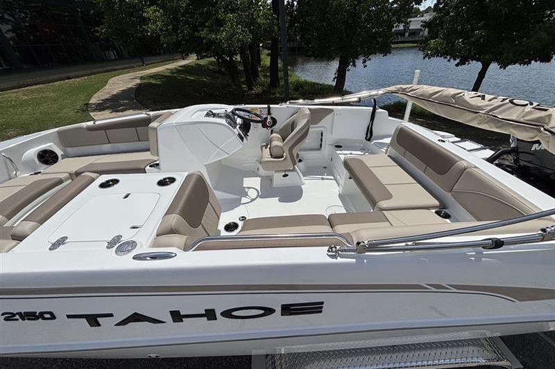 2026 Tahoe 2150 boat with spacious seating, docked near a serene lake.