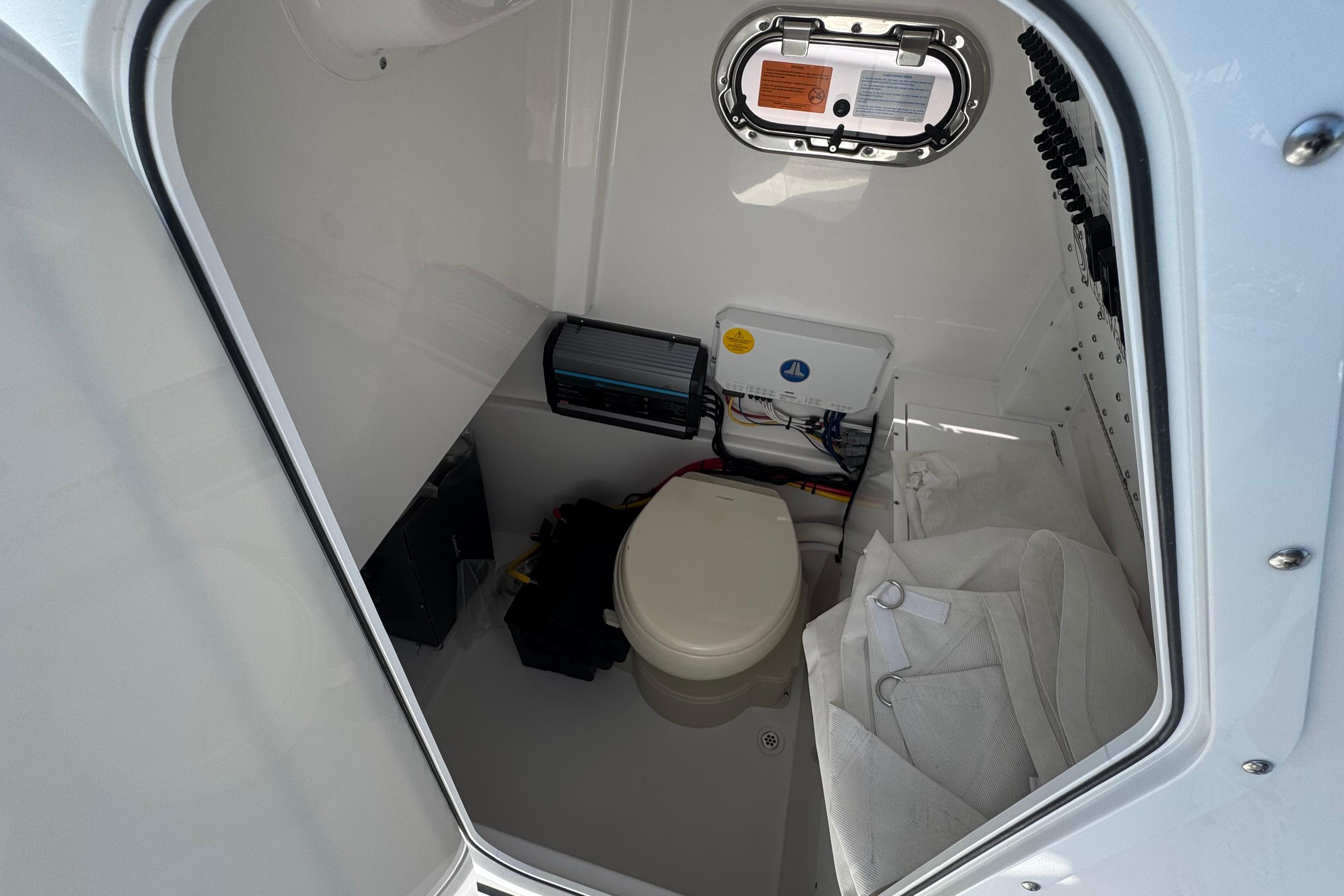 Interior of 2026 Edgewater 250CC boat showing compact marine toilet setup.