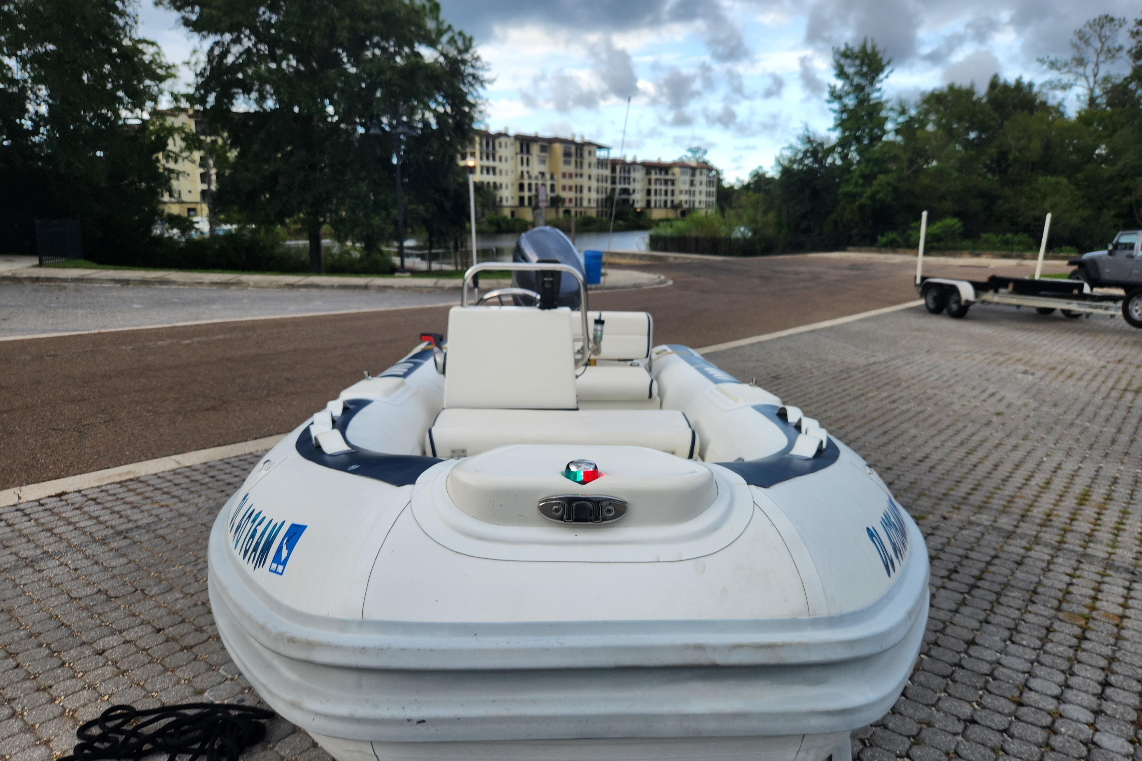 2019 Novurania DL 400 boat on a paved dock with trees and buildings in the background.