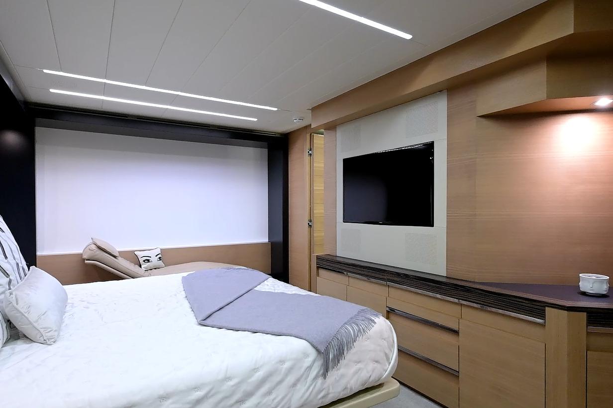 Luxurious bedroom interior on a 2015 Pershing 92 yacht, featuring modern design and a flat-screen TV.