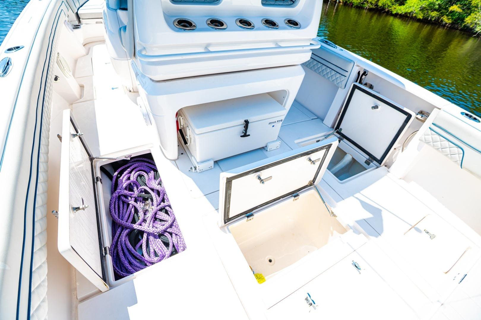 2018 Intrepid 327 Center Console boat with open storage compartments and purple ropes.