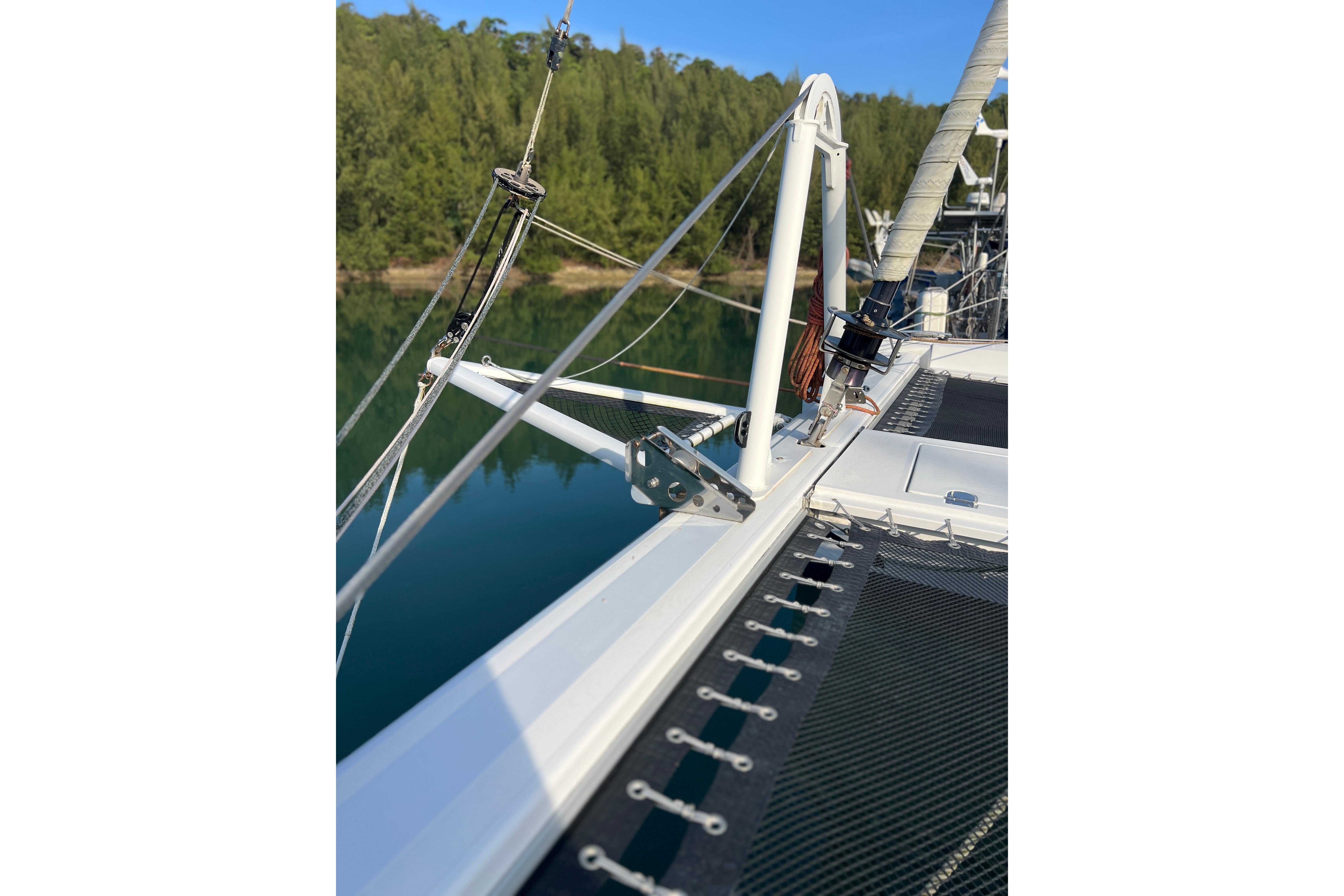 2015 Outremer 51 catamaran deck with rigging, near lush green shoreline.