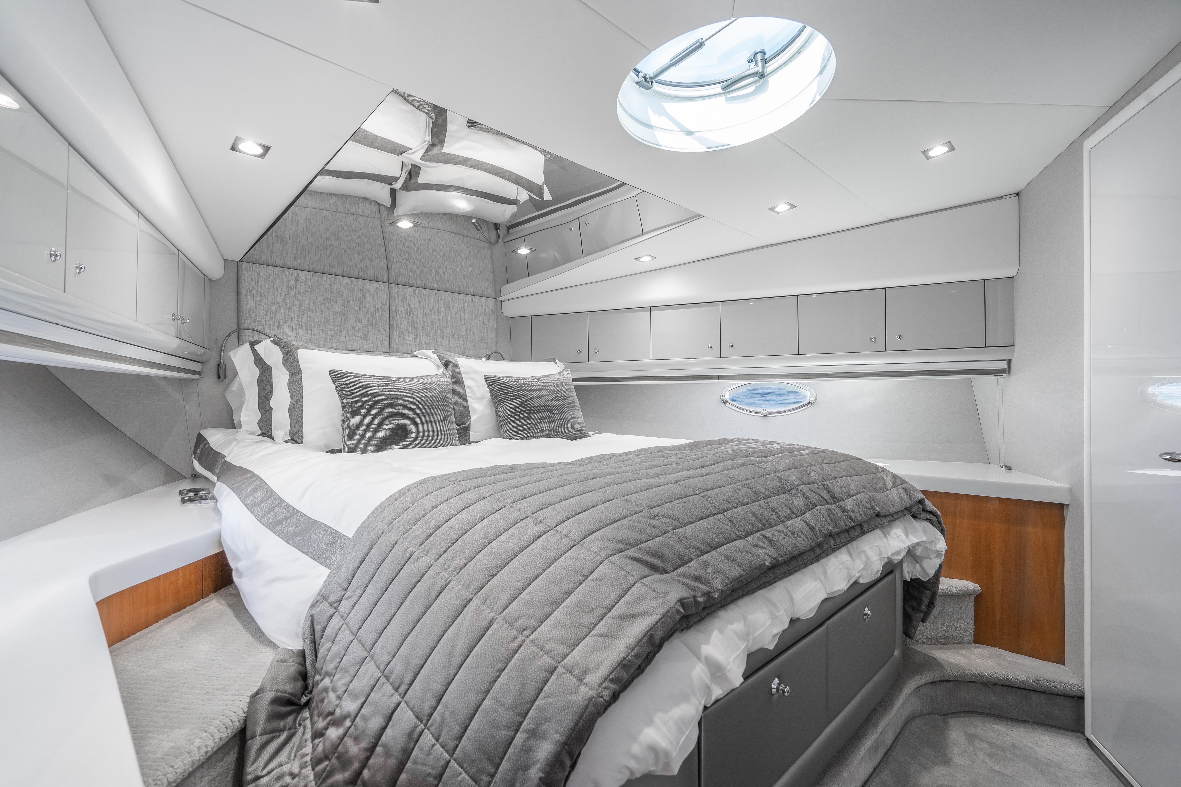 Luxurious bedroom interior of 2021 Sunseeker Predator 68 yacht with modern design and elegant bedding.