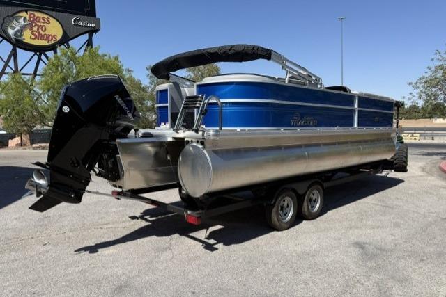2026 Sun Tracker Party Barge 24 XP3 pontoon boat on trailer, parked near Bass Pro Shops.